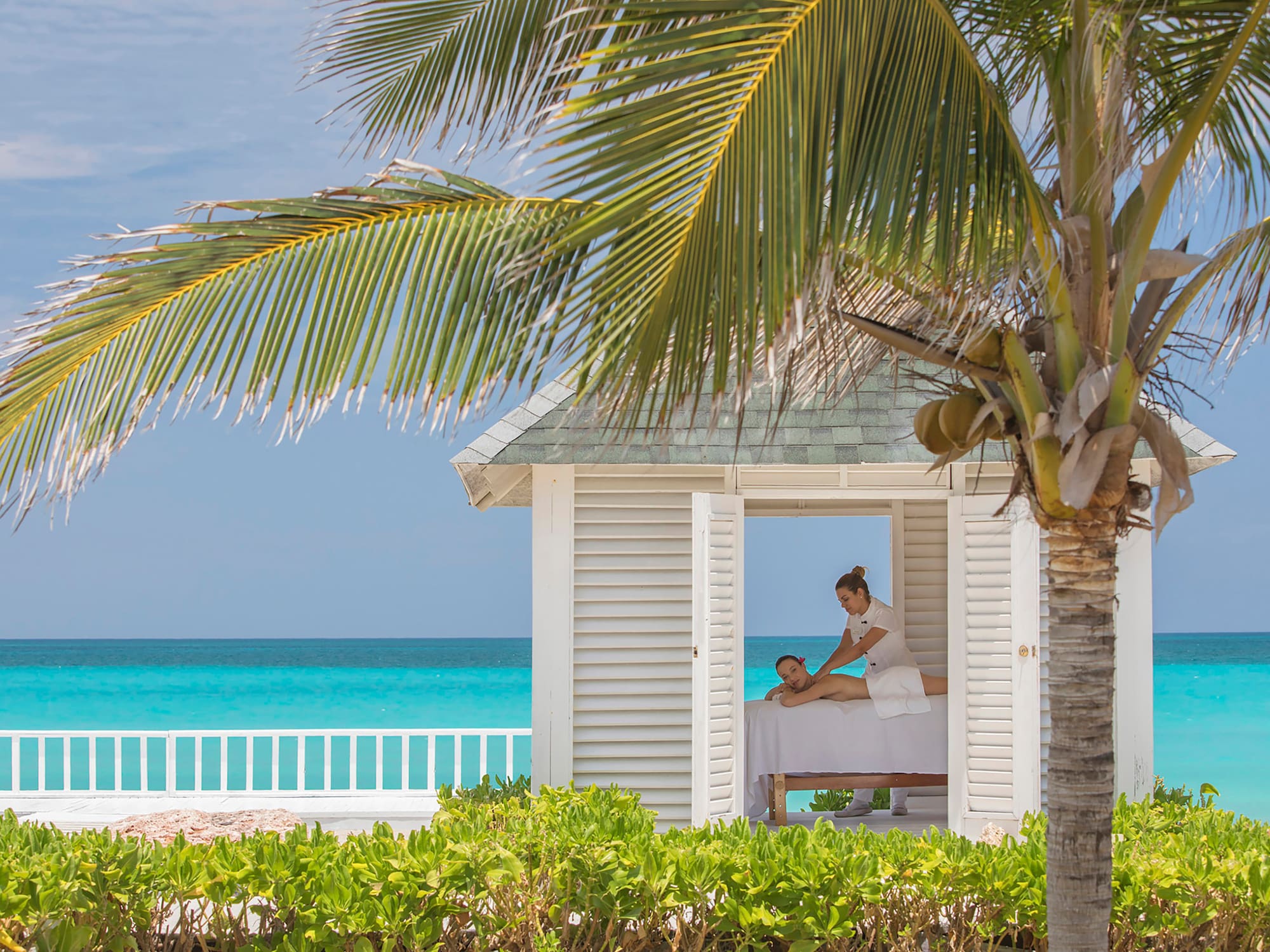 a woman getting a massage from a woman on a bed outside