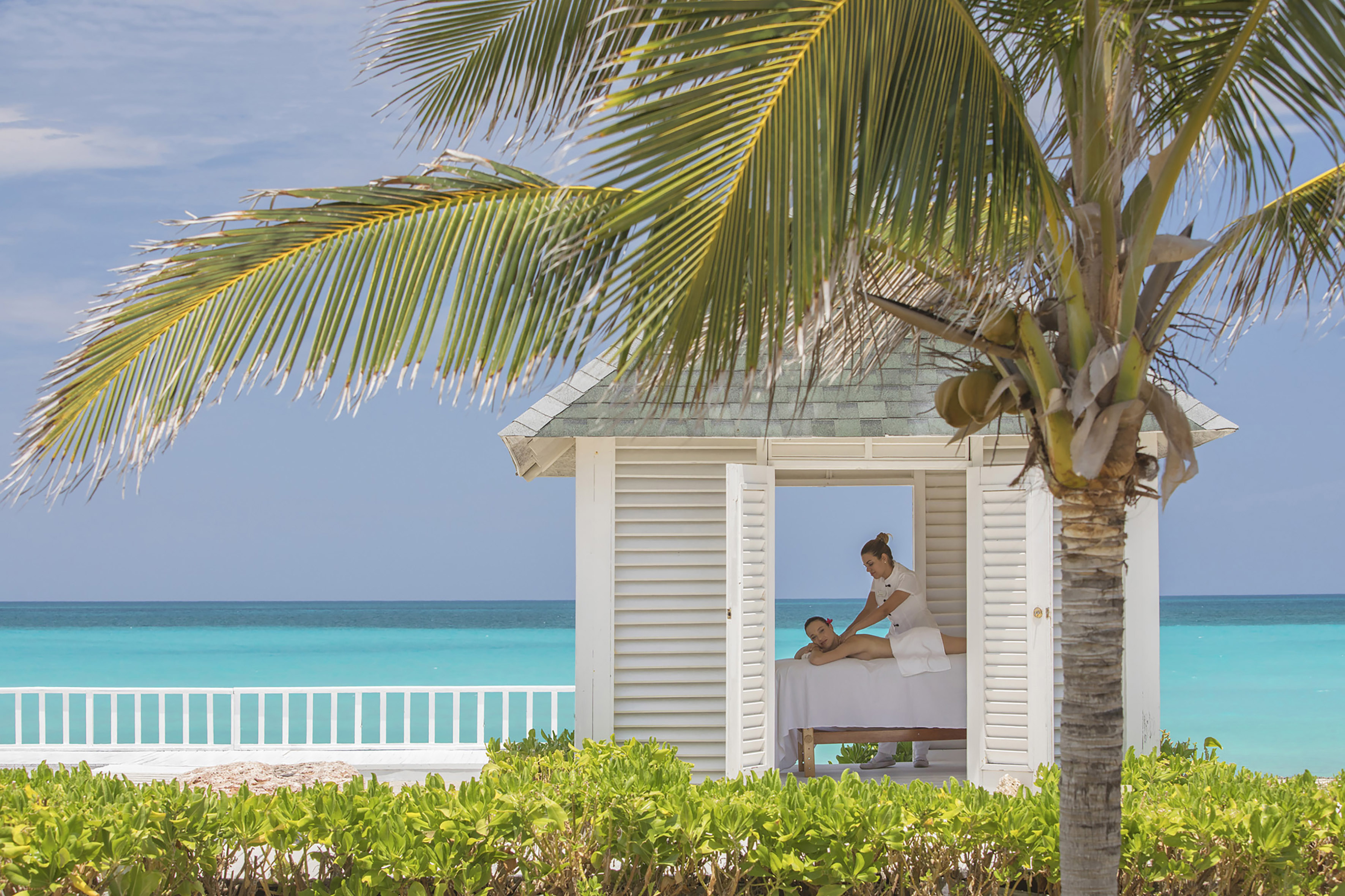 a woman getting a massage from a woman on a bed outside