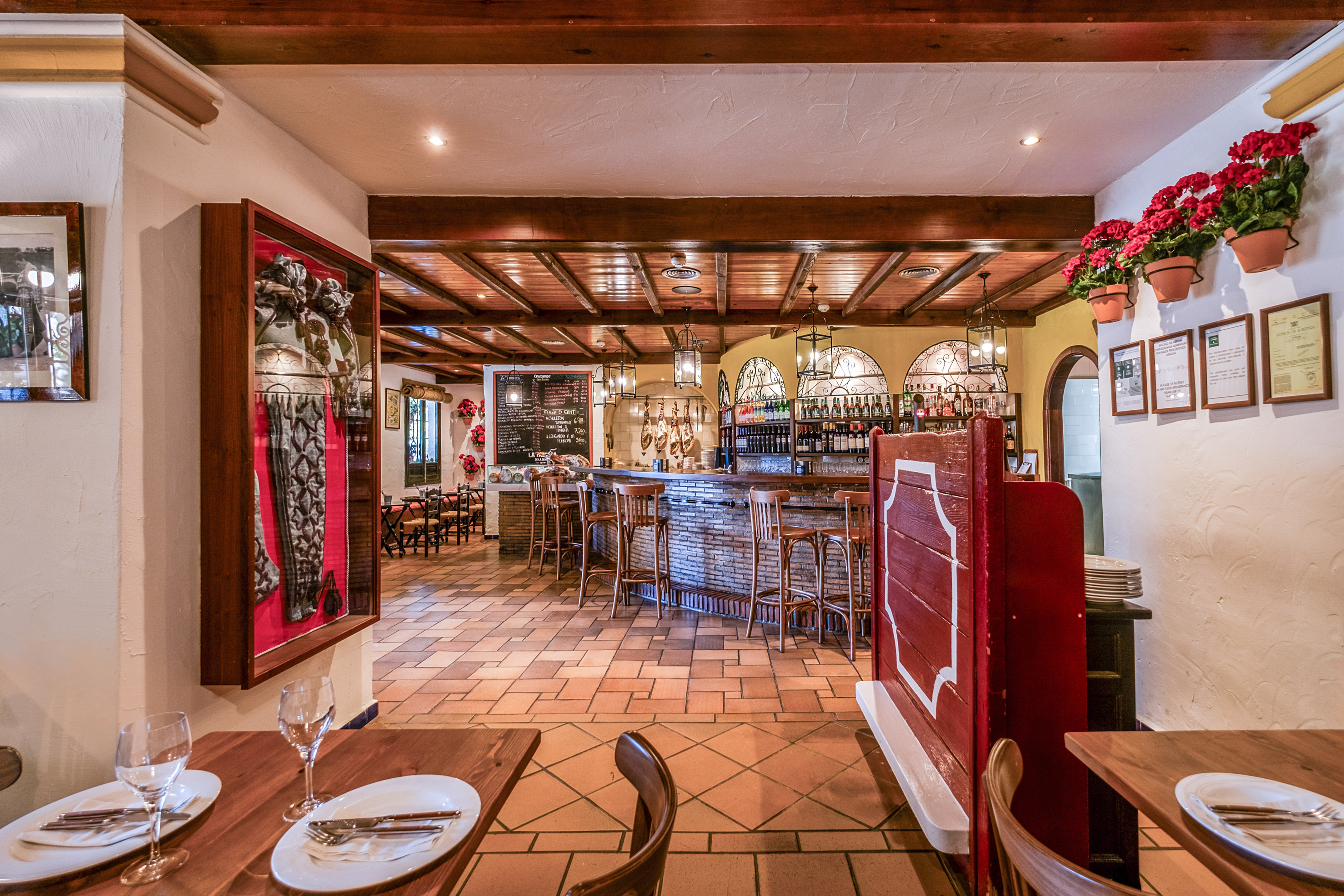 Rustic Spanish restaurant interior with bar, hanging hams, and wooden beams.