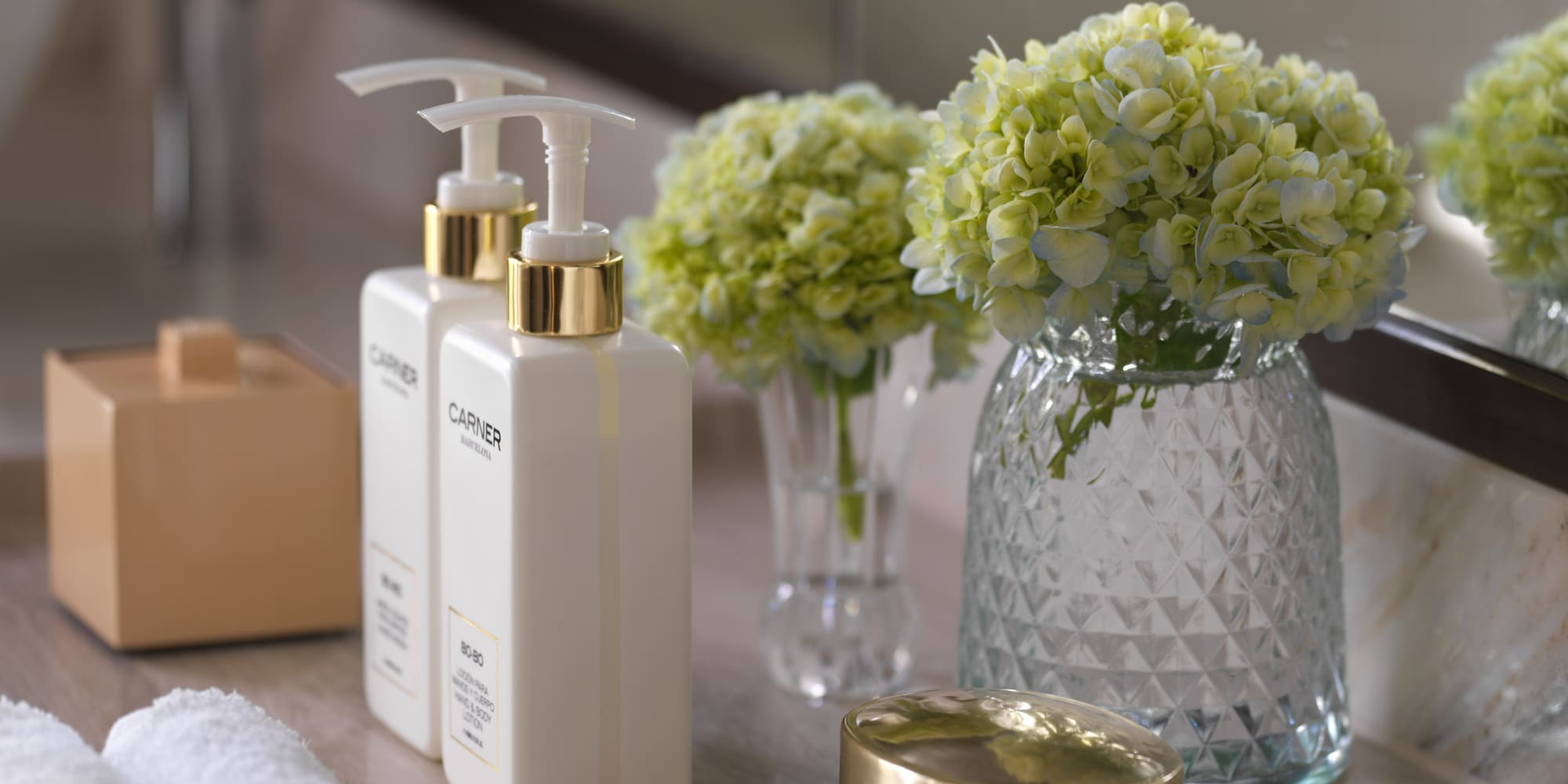 a group of white bottles with a gold lid next to a vase of flowers