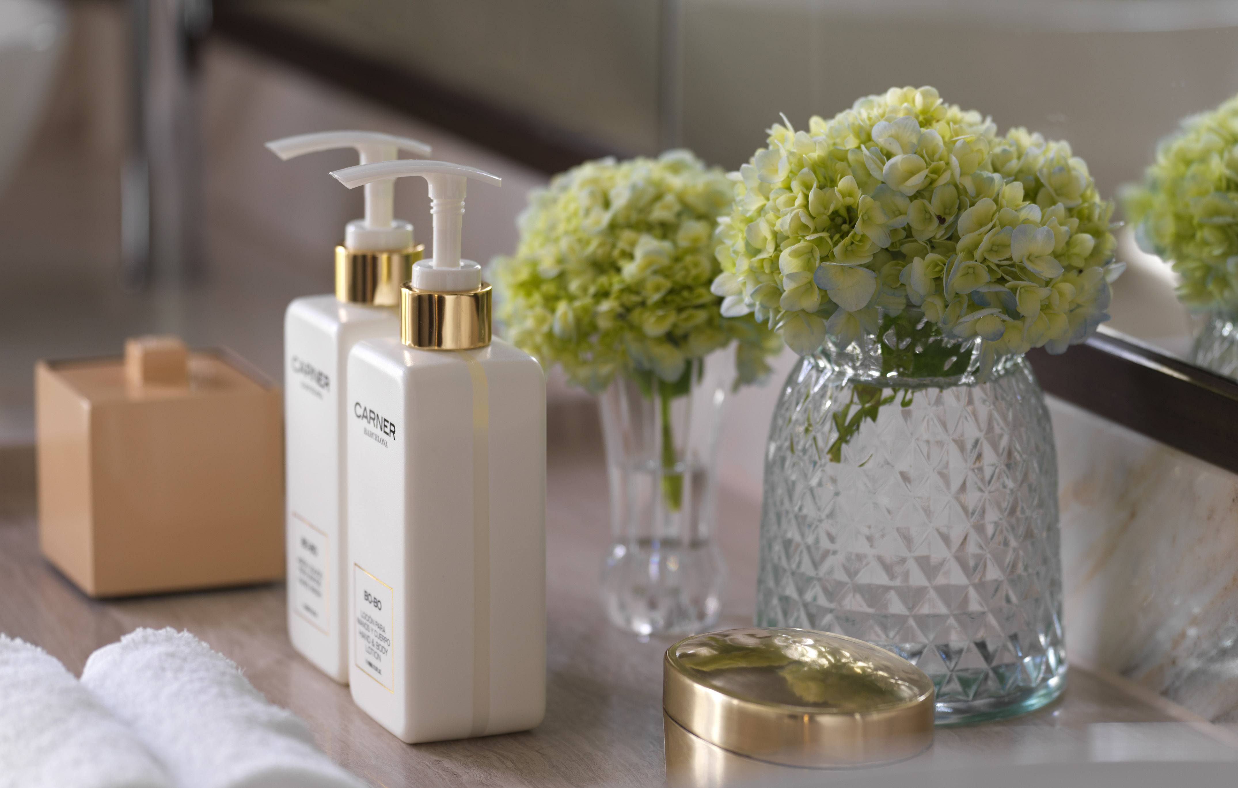 Hotel bathroom amenities: soap, lotion dispensers, and fresh hydrangeas.