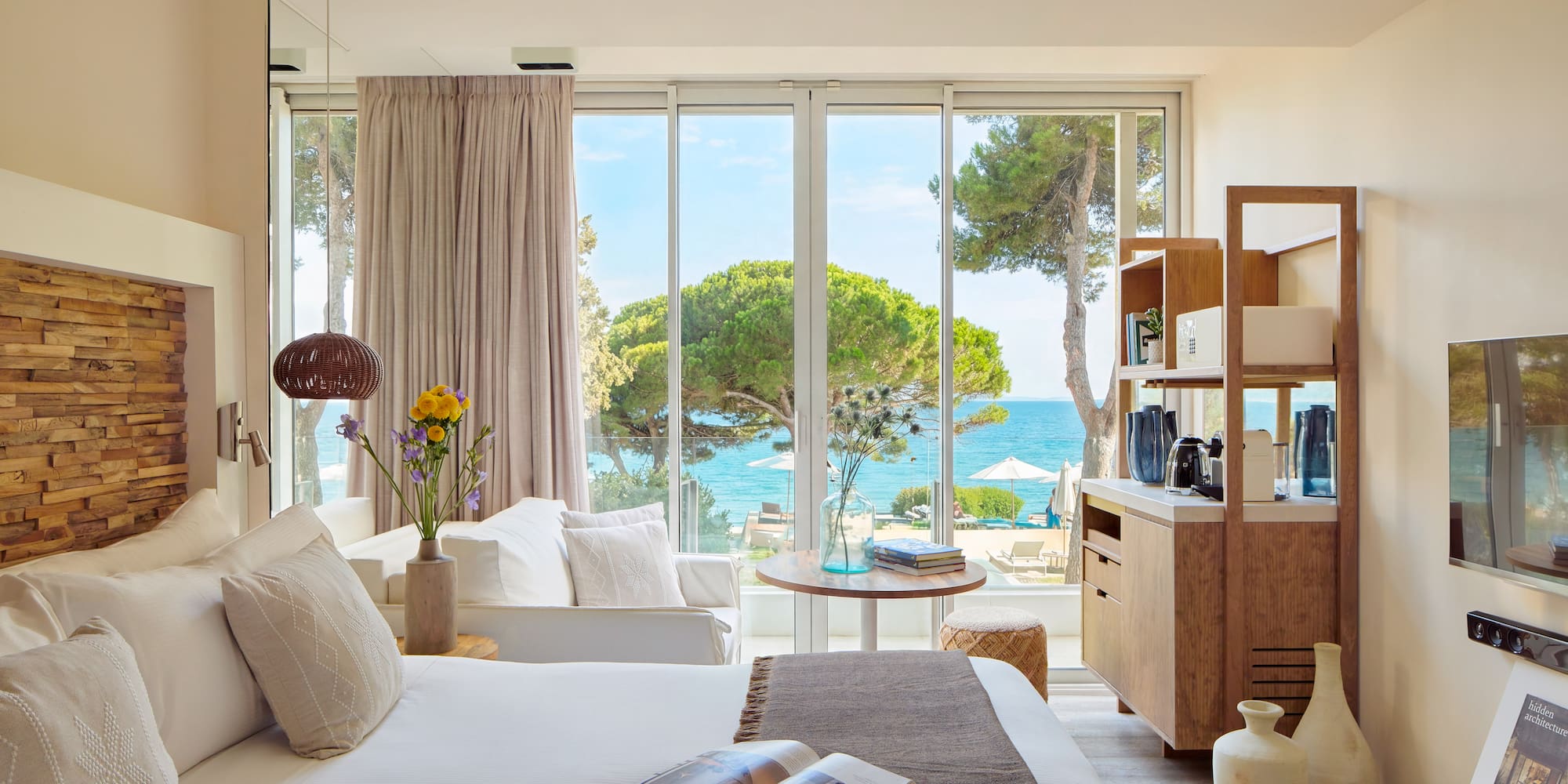 a room with a bed and a table and chairs and a window with trees and water