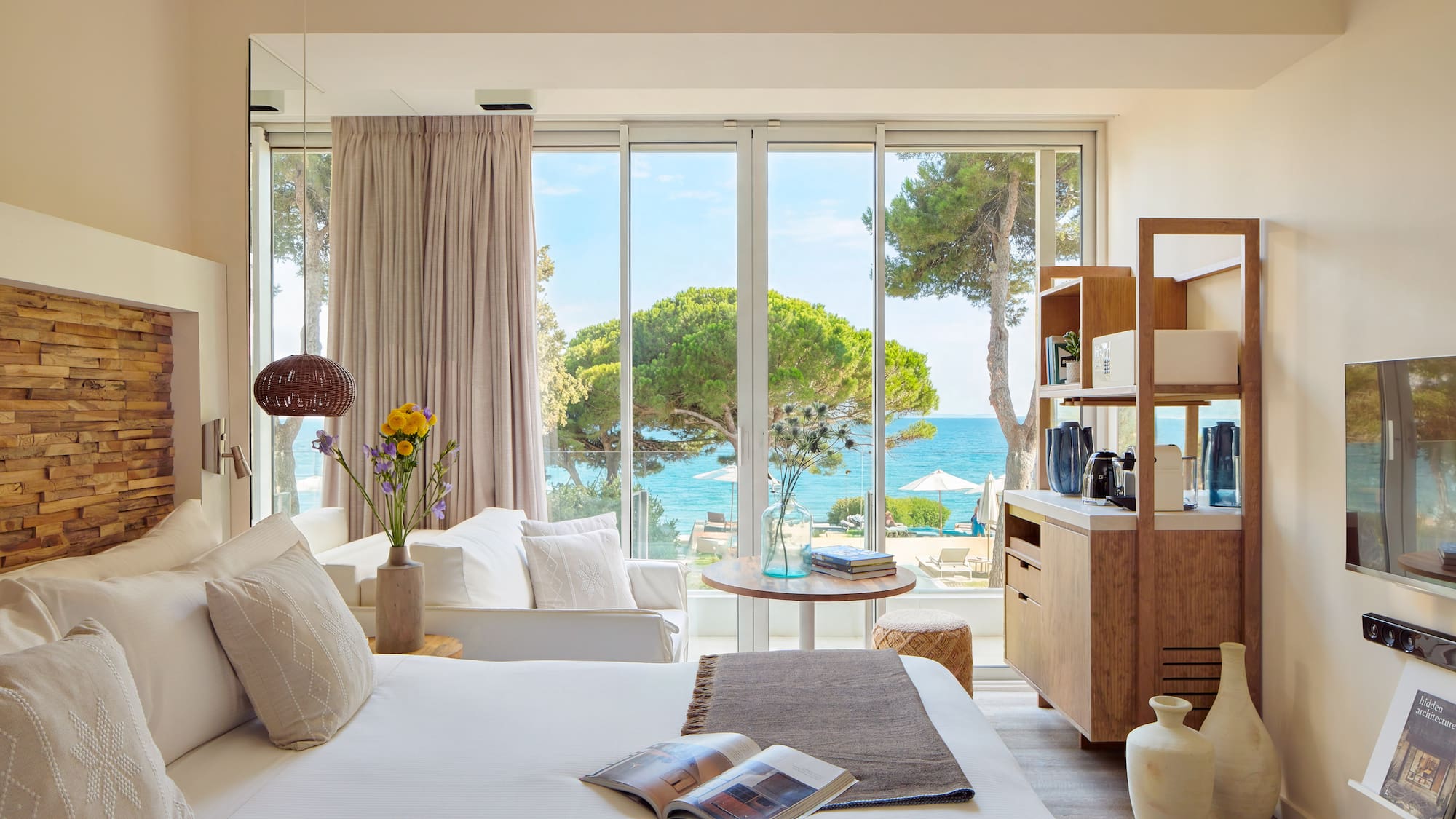 a room with a bed and a table and chairs and a window with trees and water