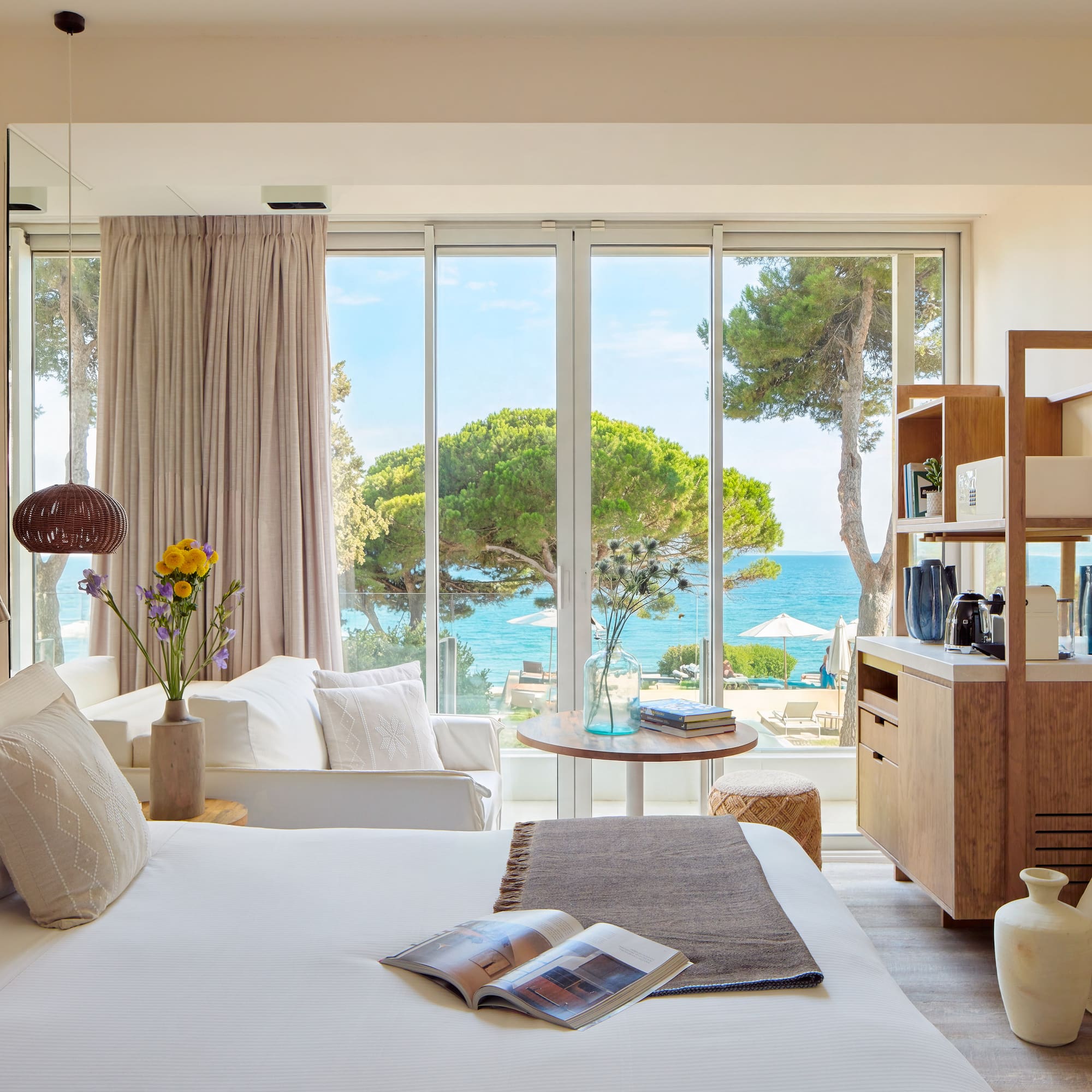 a room with a bed and a table and chairs and a window with trees and water