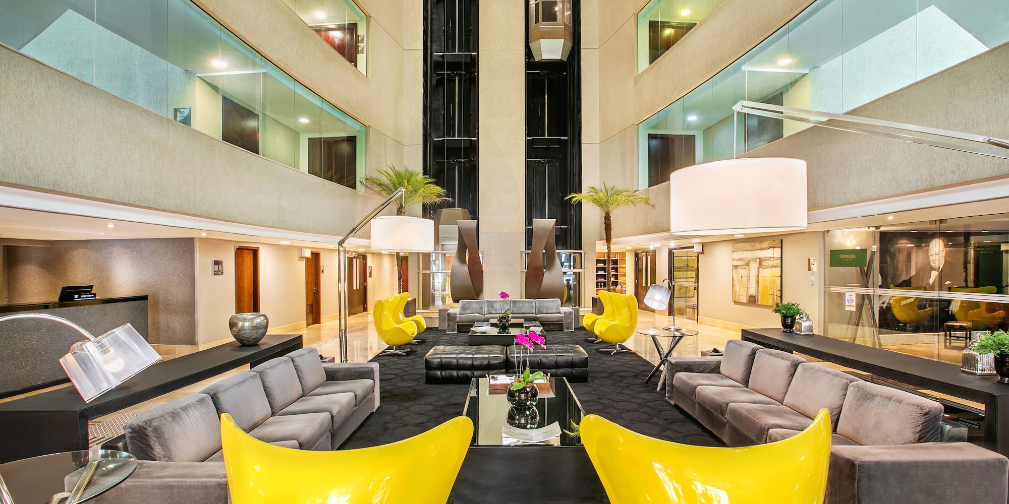 a large lobby with a large black couch and yellow chairs