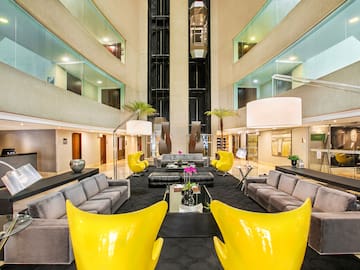 a large lobby with a large black couch and yellow chairs