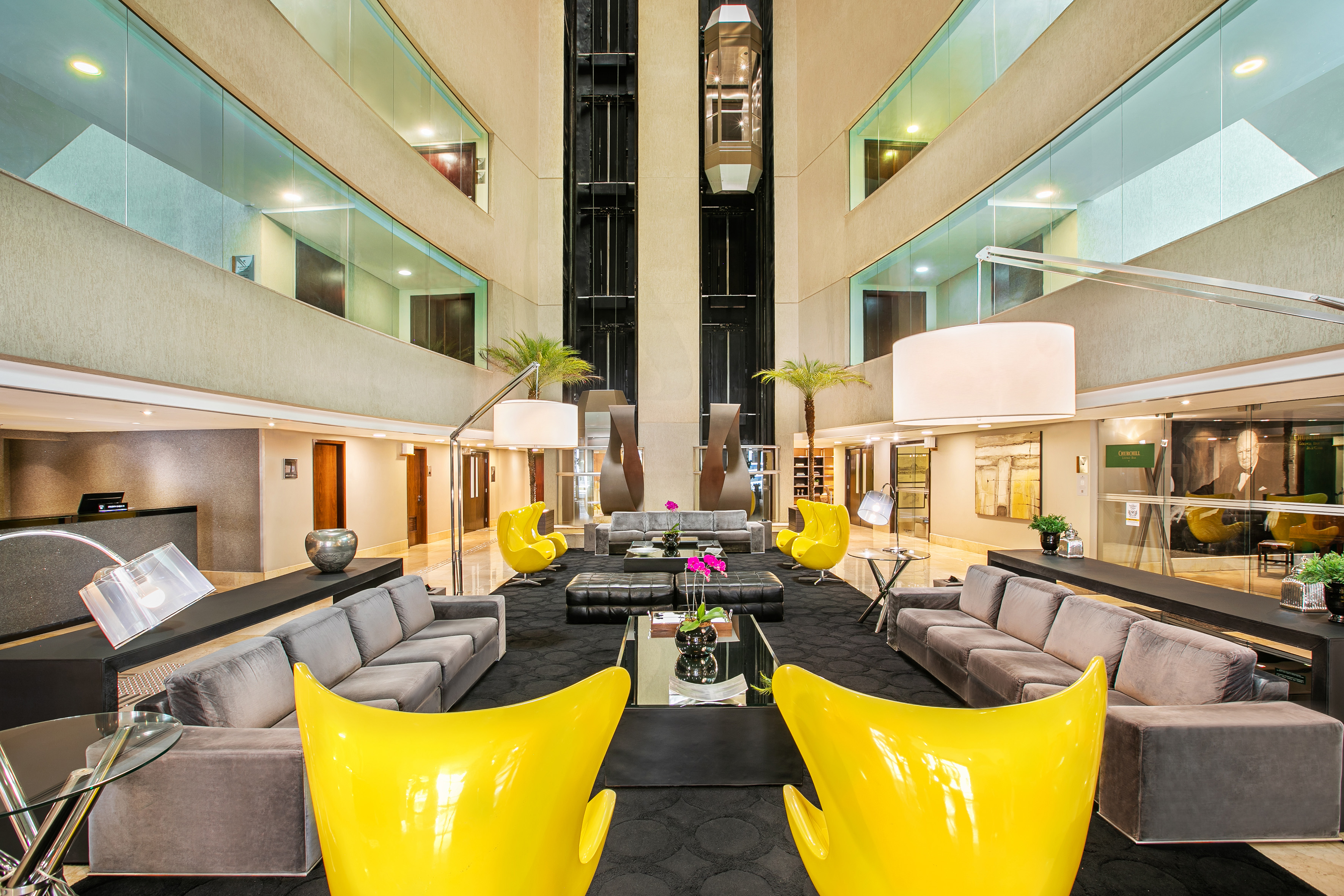 a large lobby with a large black couch and yellow chairs