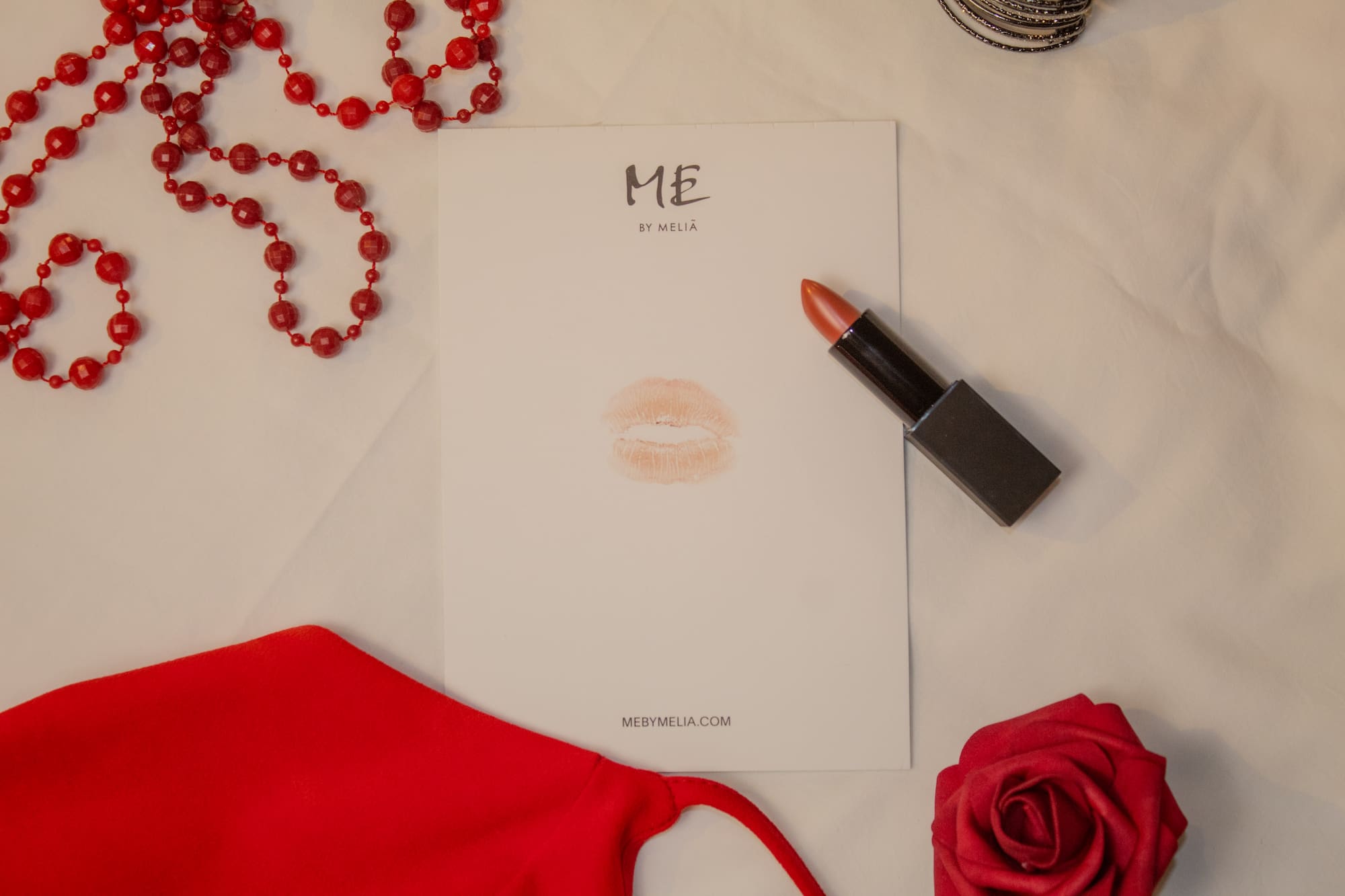 a note with lipstick and a rose on a white surface