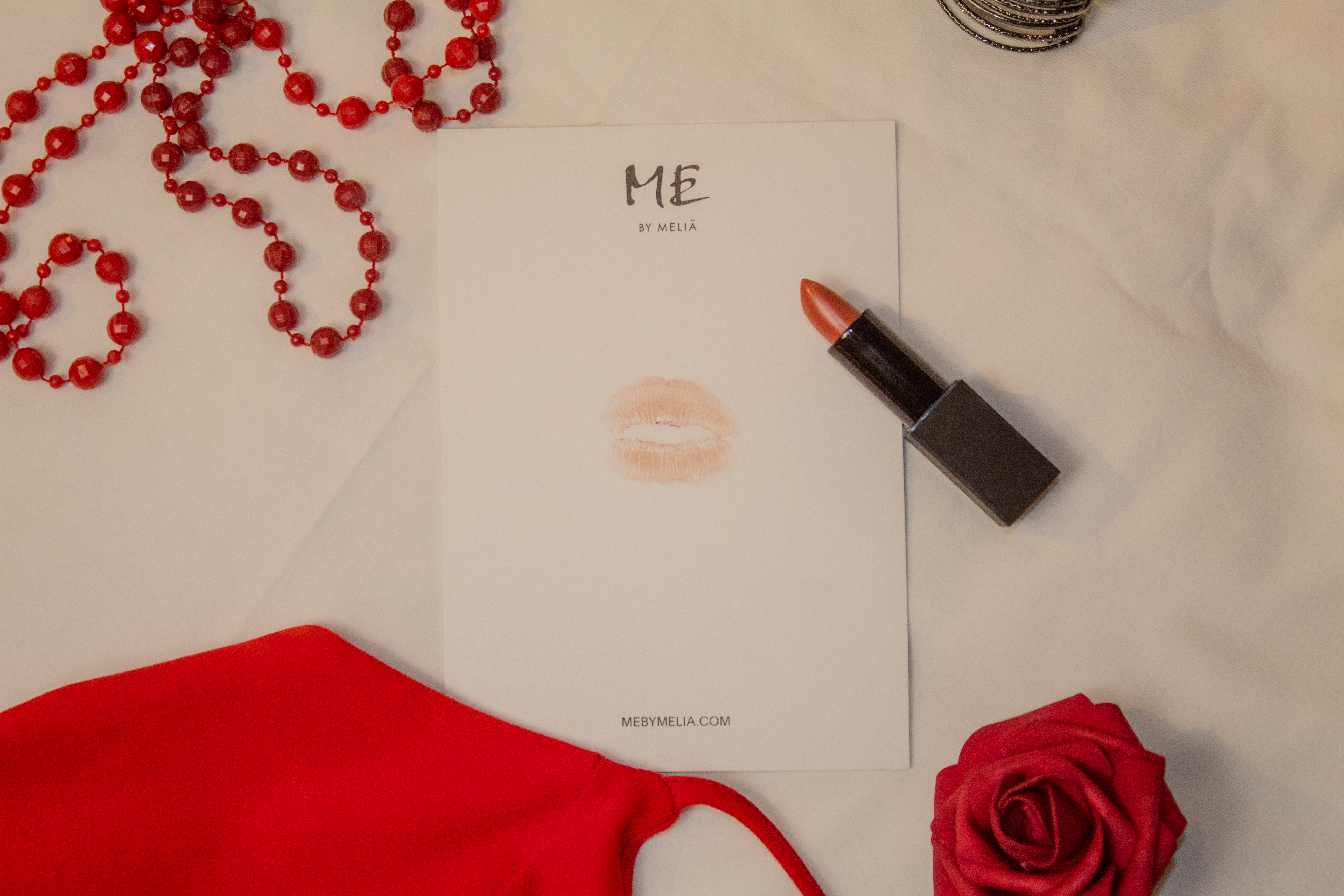 a note with lipstick and a rose on a white surface