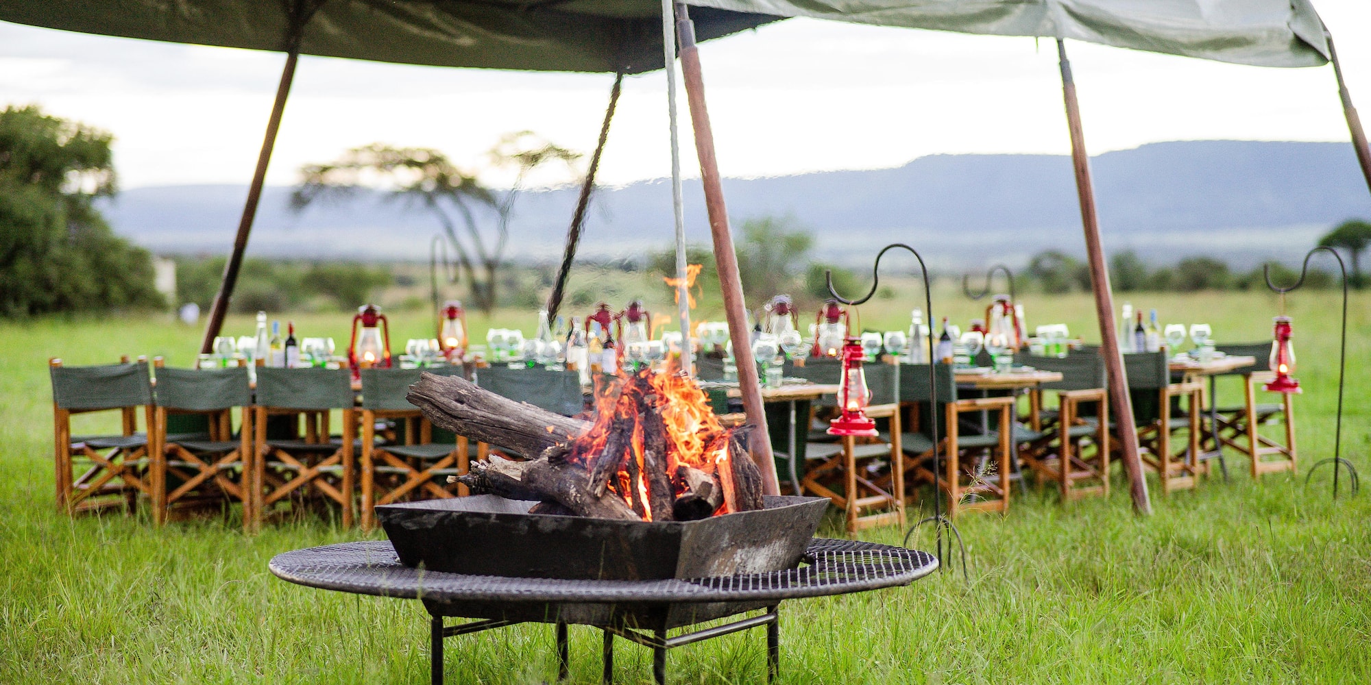 a fire pit with a tent and tables and chairs