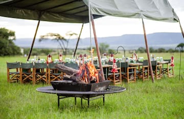 a fire pit with a tent and tables and chairs