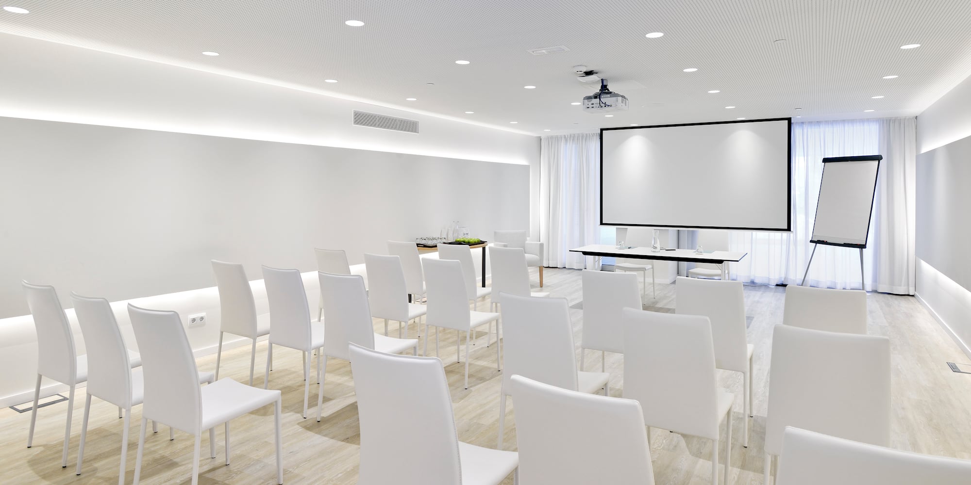 a room with white chairs and a projector screen