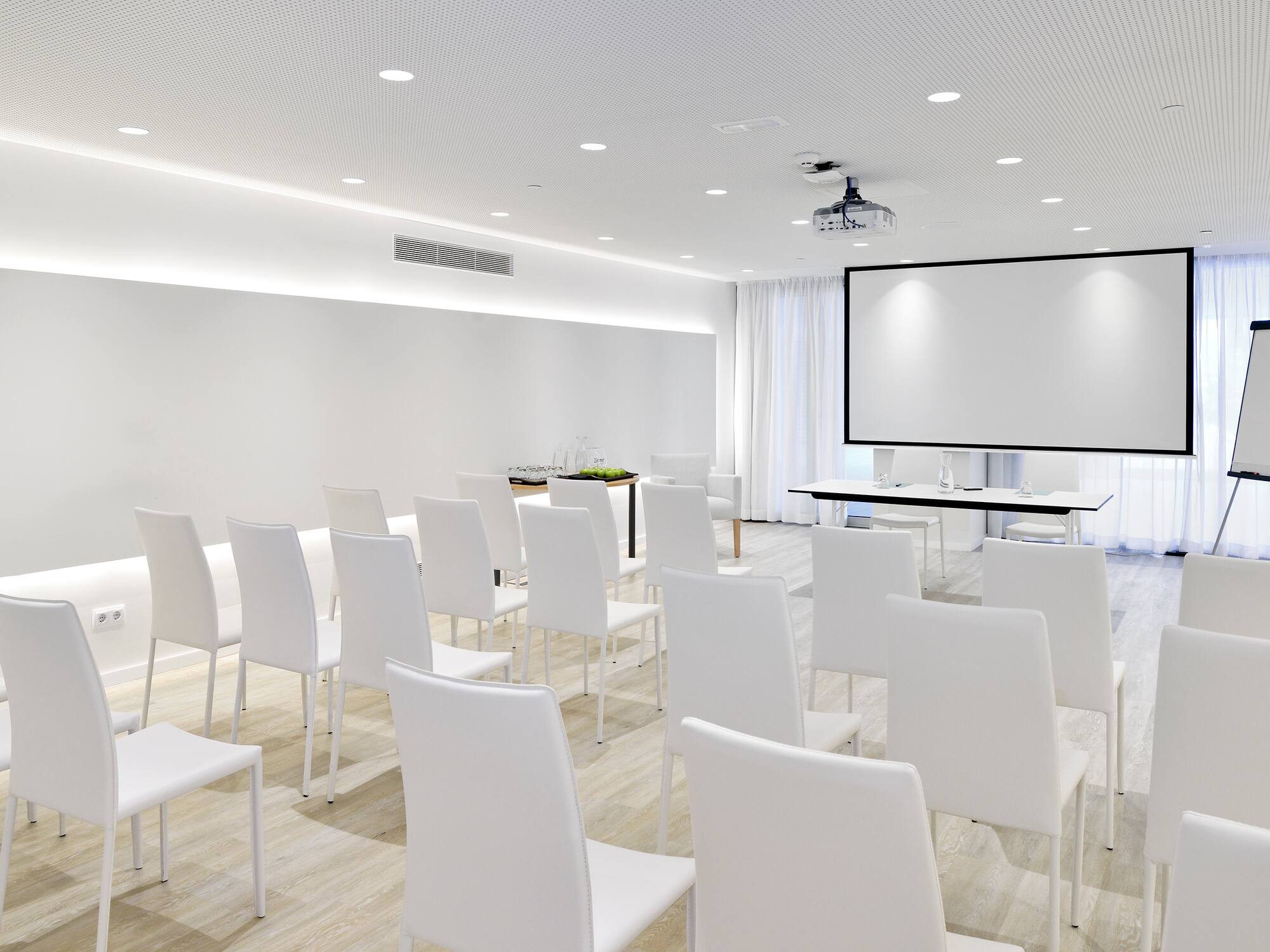 a room with white chairs and a projector screen