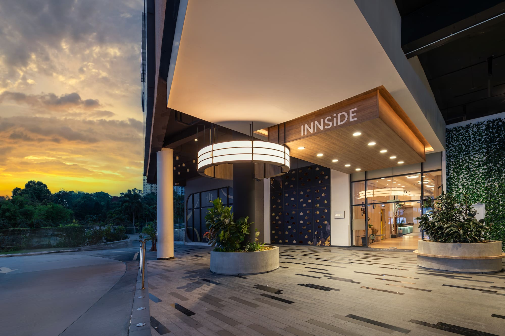 INNSIDE hotel entrance at sunset, modern architecture with circular light and greenery.