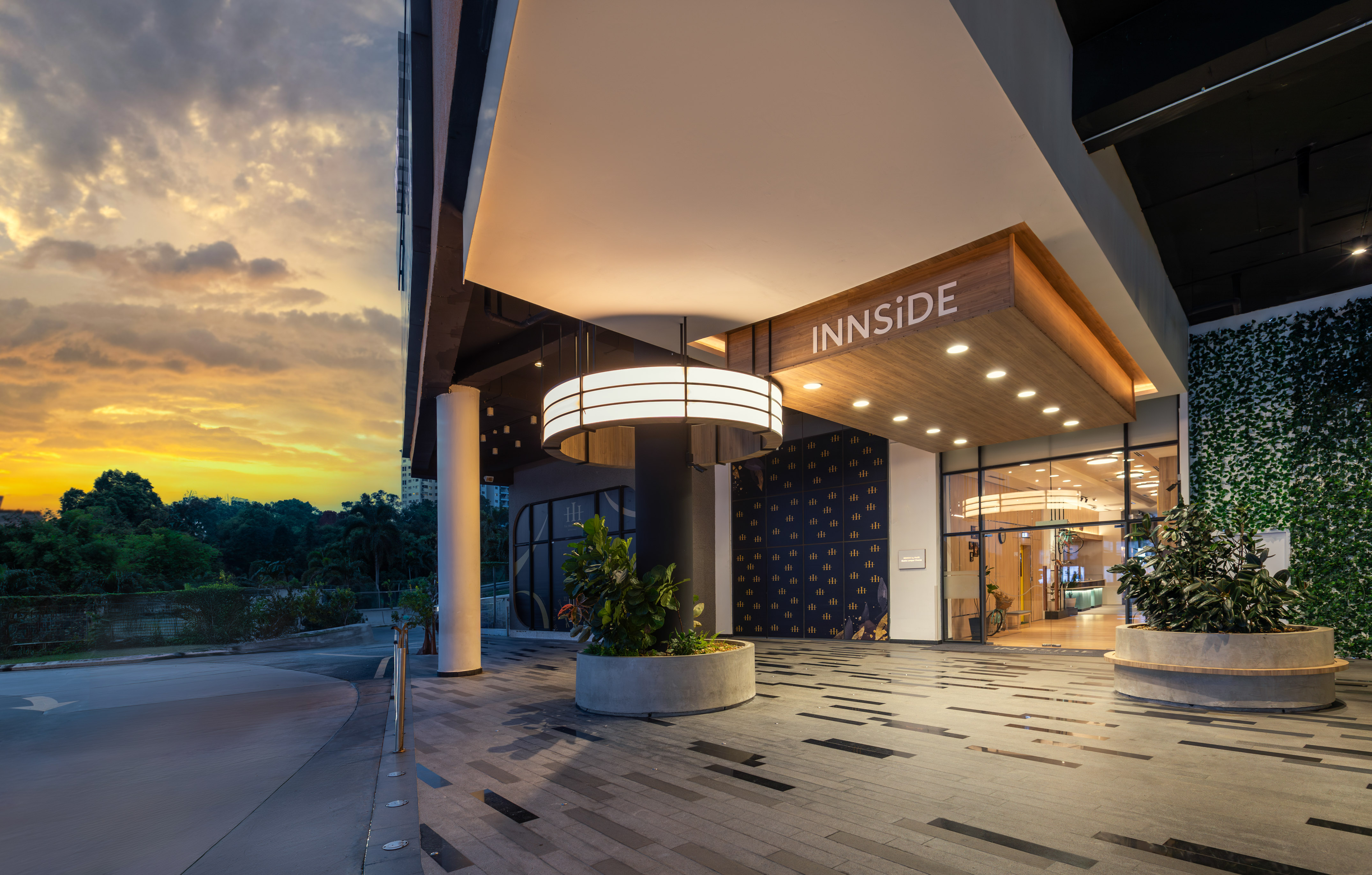 INNSIDE hotel entrance at sunset, modern architecture with circular light and greenery.