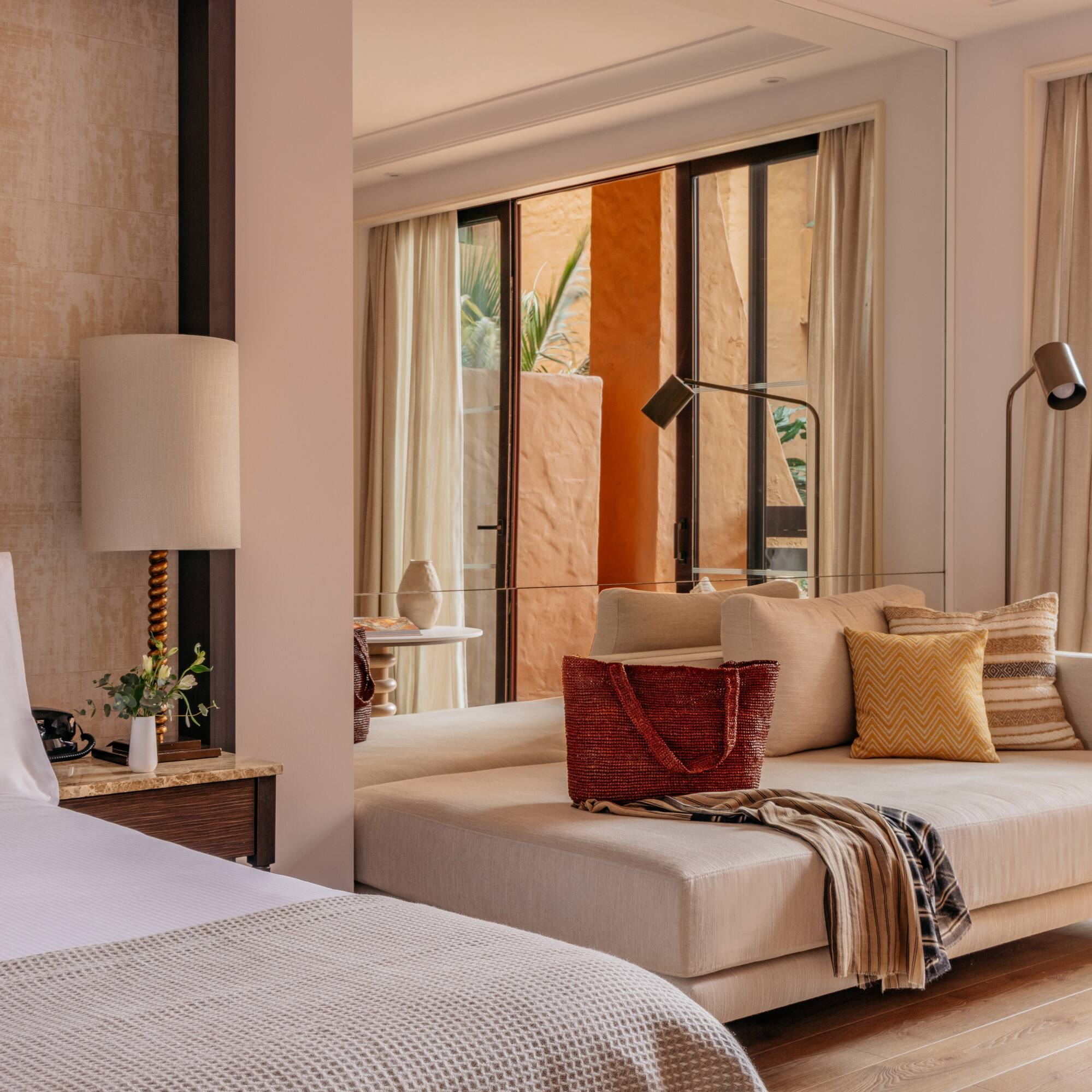 Modern resort suite with bed, daybed, and warm terracotta patio view.