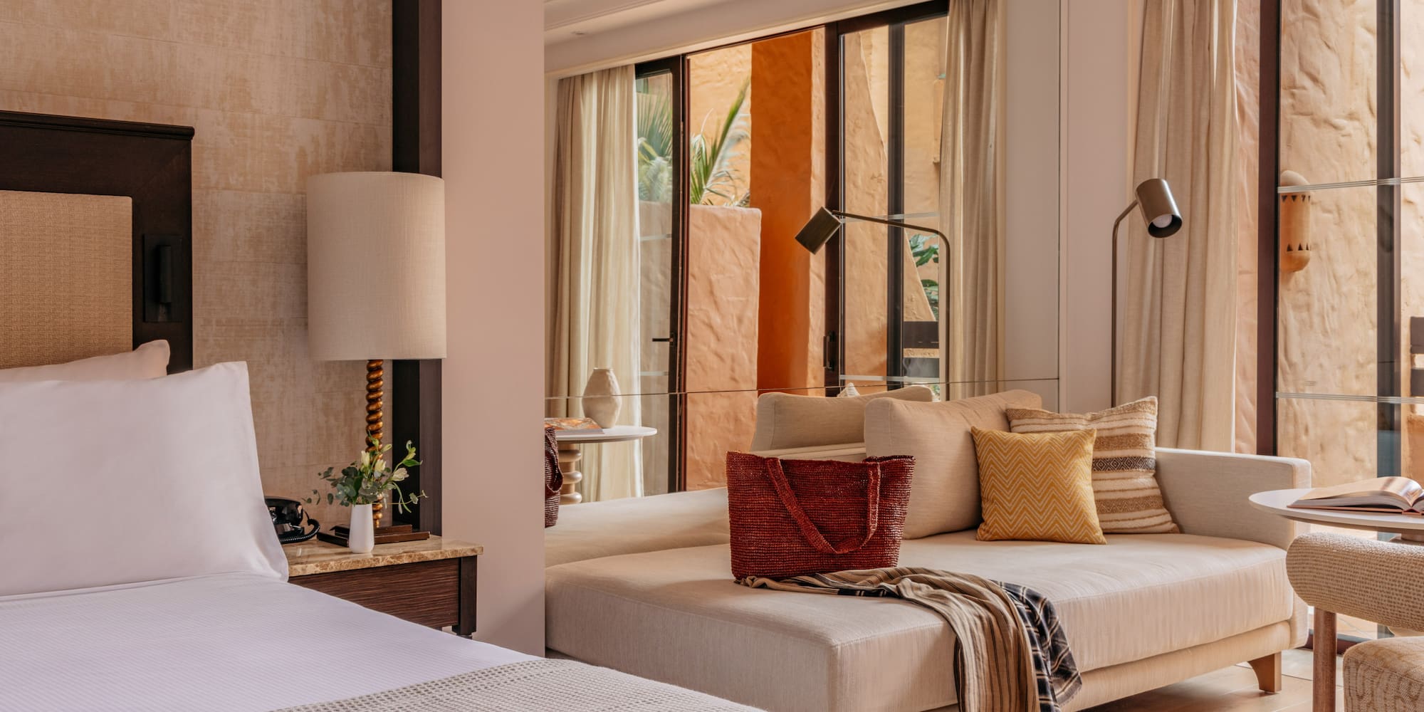Modern resort suite with bed, daybed, and warm terracotta patio view.