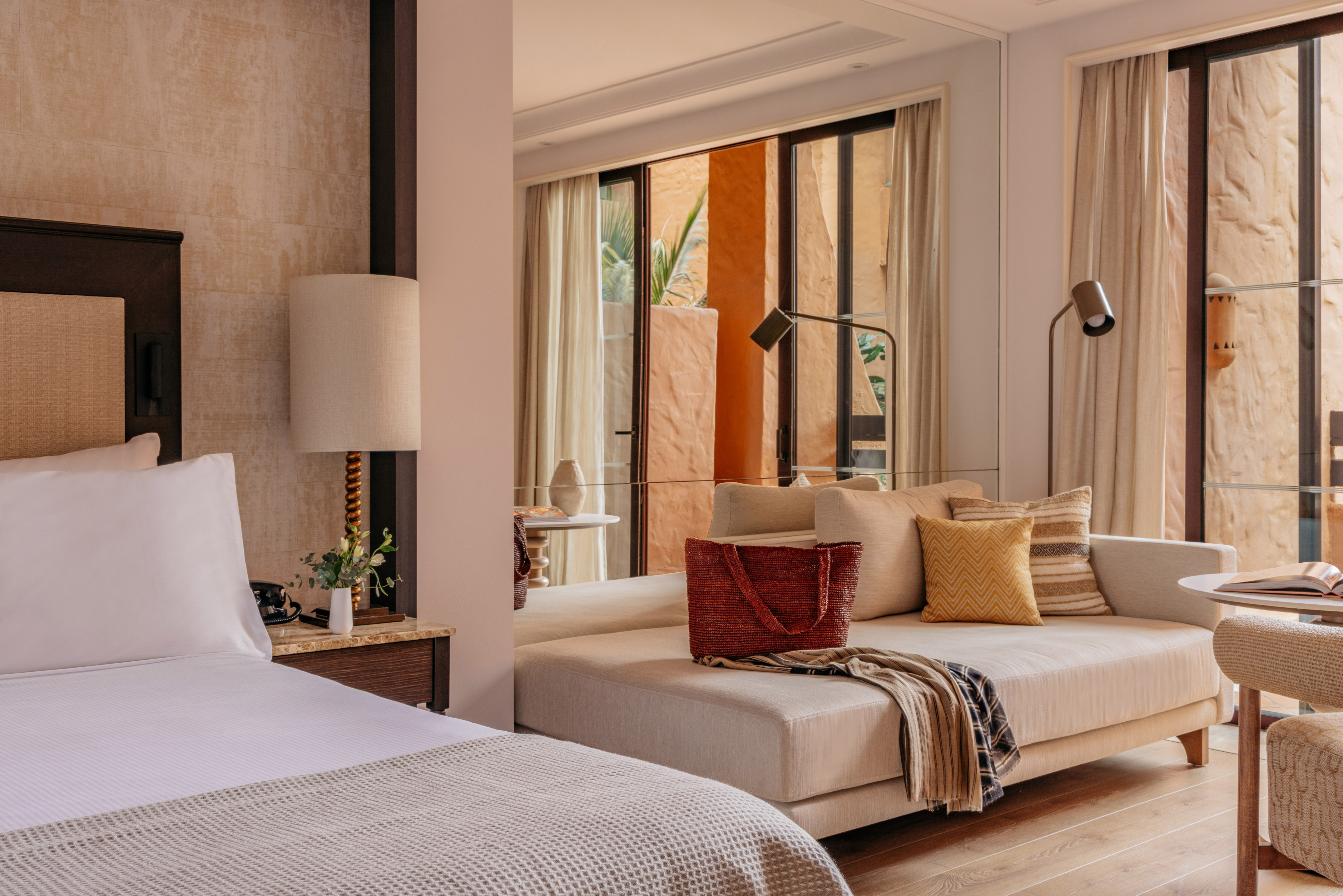 Modern resort suite with bed, daybed, and warm terracotta patio view.