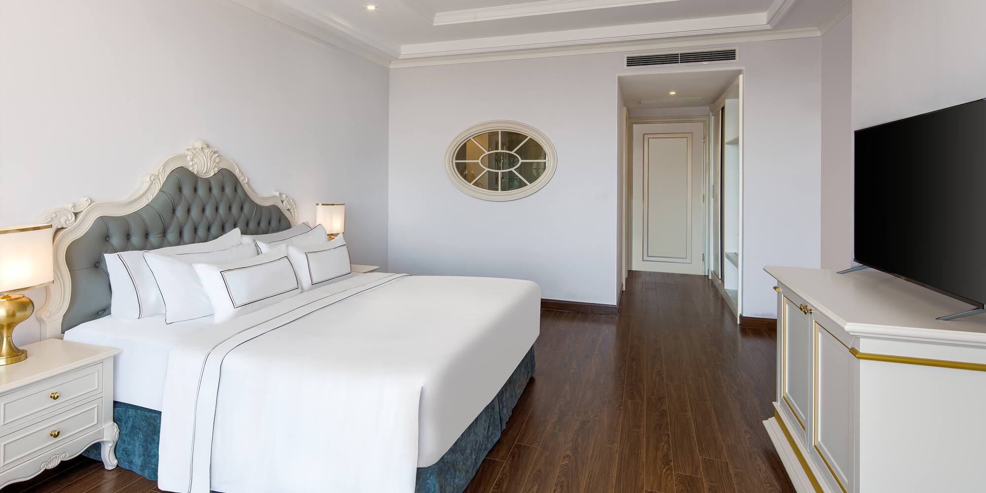 a bedroom with a white bed and wood floor