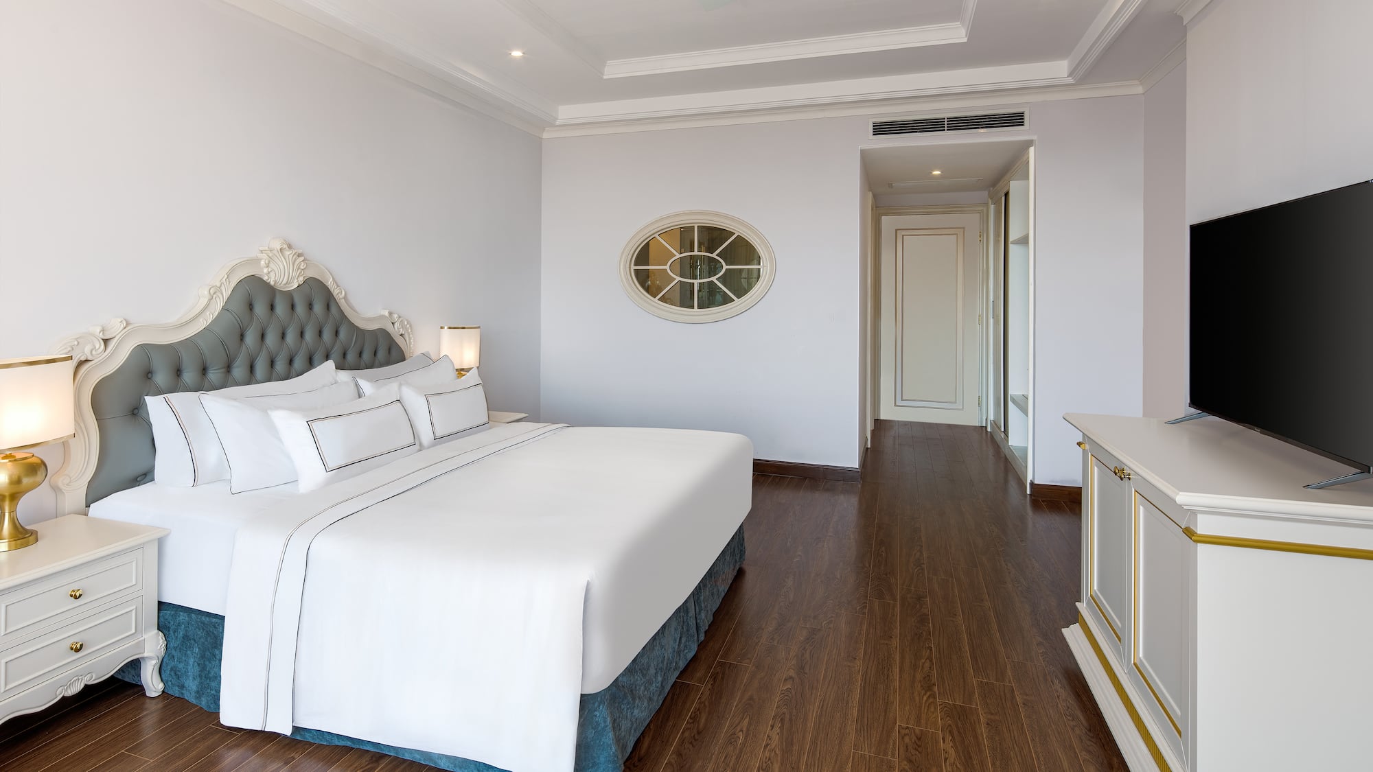 a bedroom with a white bed and wood floor