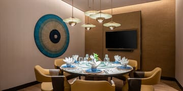 a dining room with a table set with chairs and a television