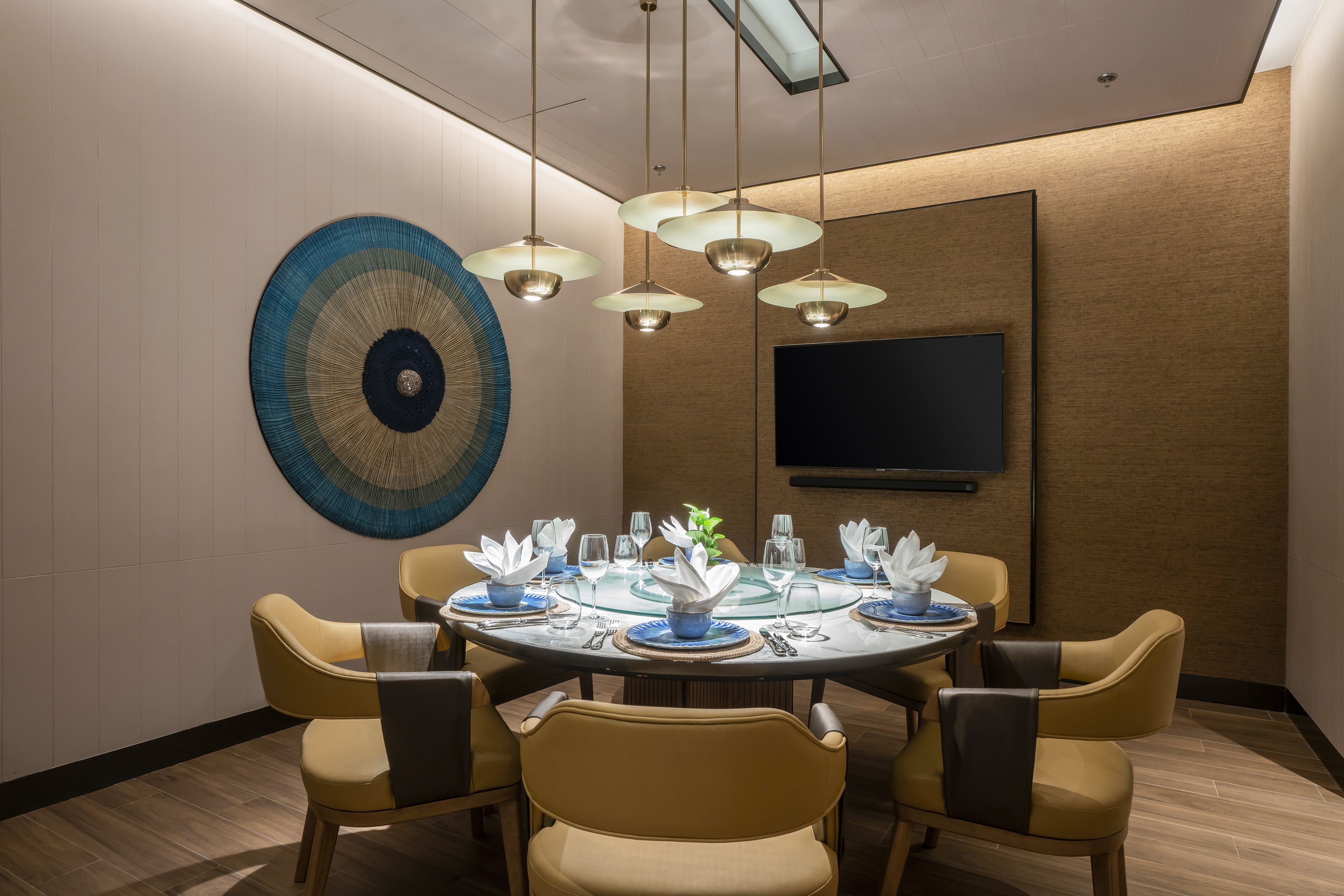 Modern private dining room, round table, gold chairs, contemporary lighting.