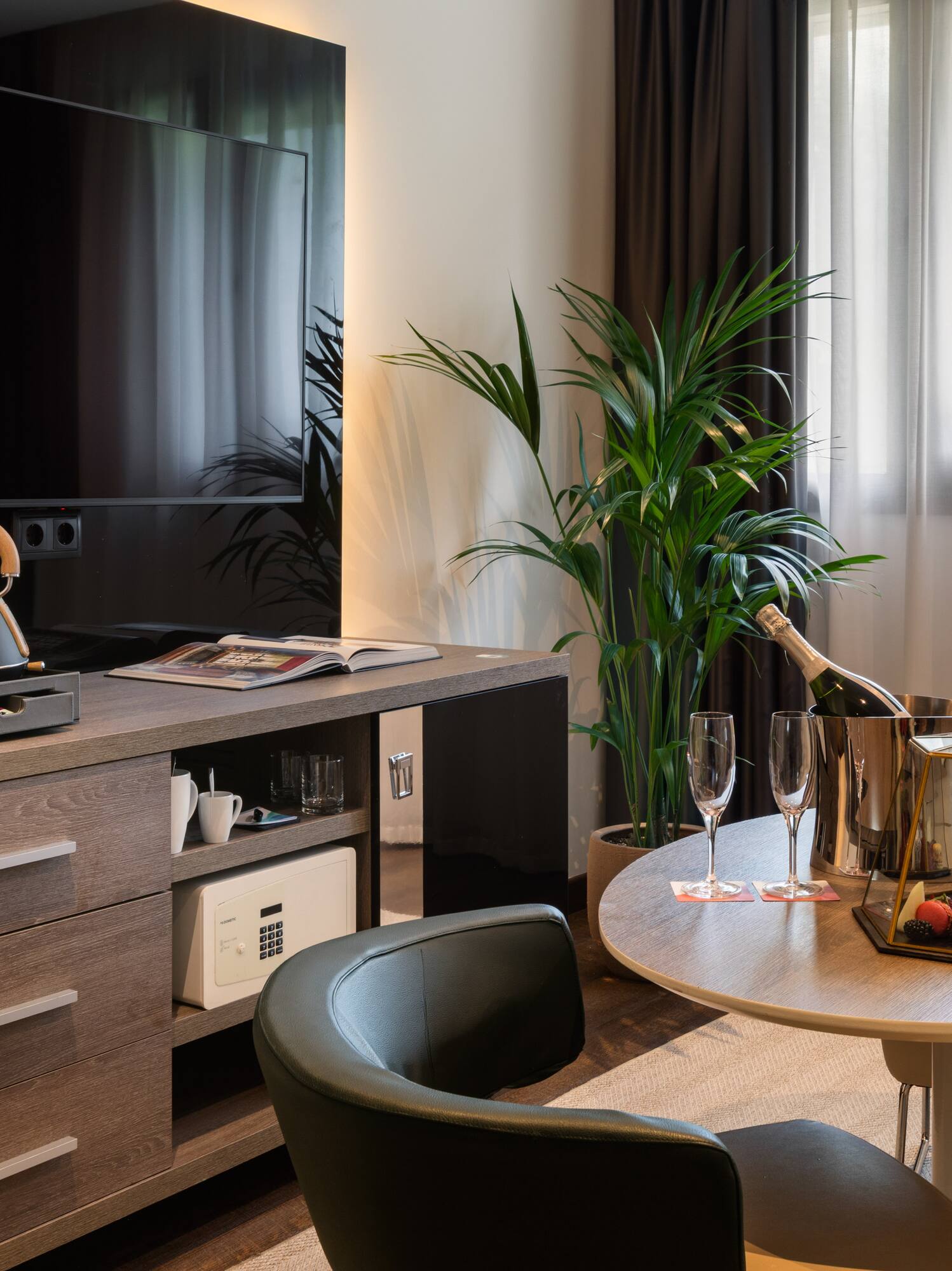 Habitación de hotel de lujo con TV, minibar, Nespresso, champagne y mesa.