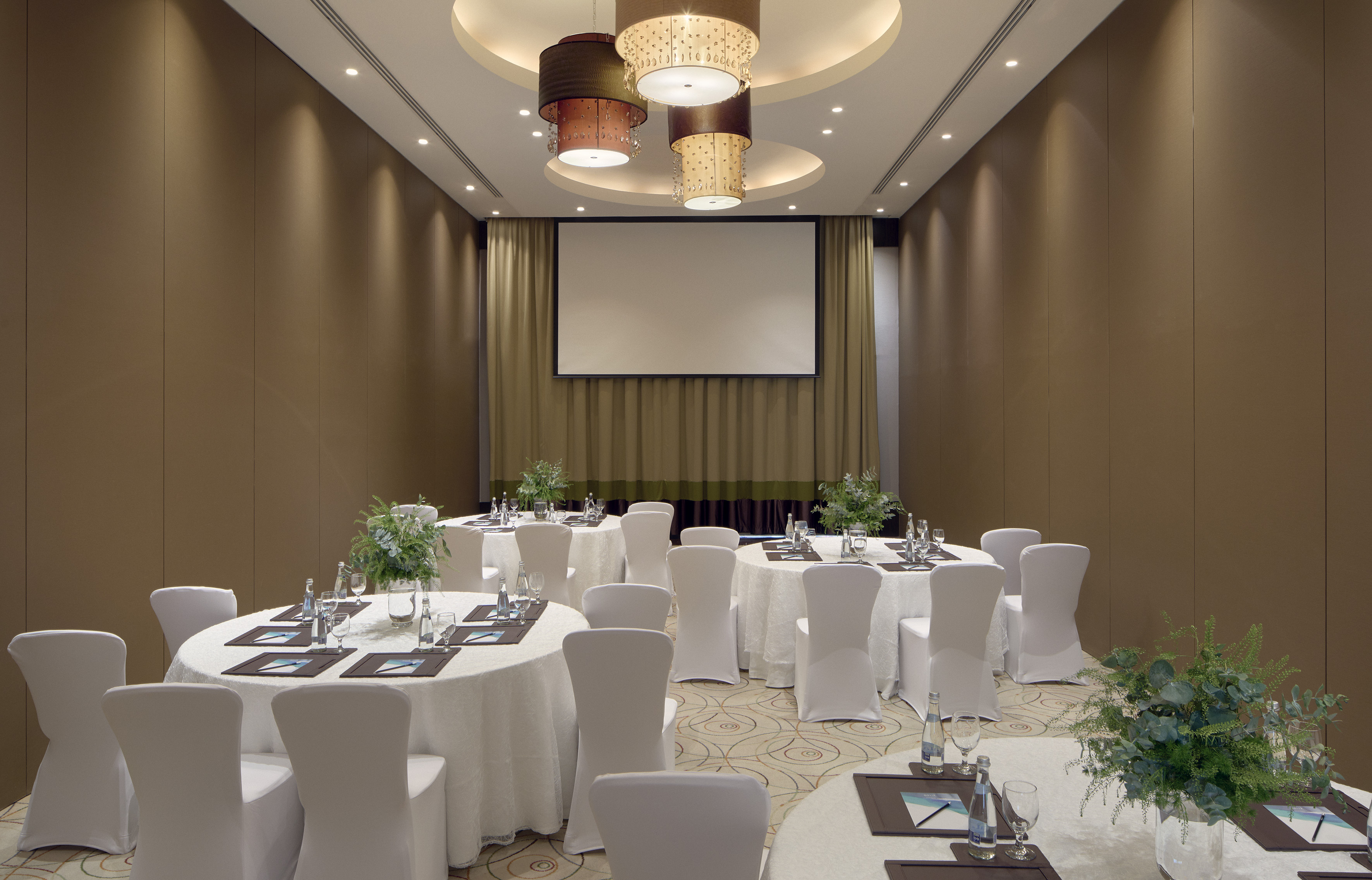 Conference room with round tables, white chairs, and presentation screen.