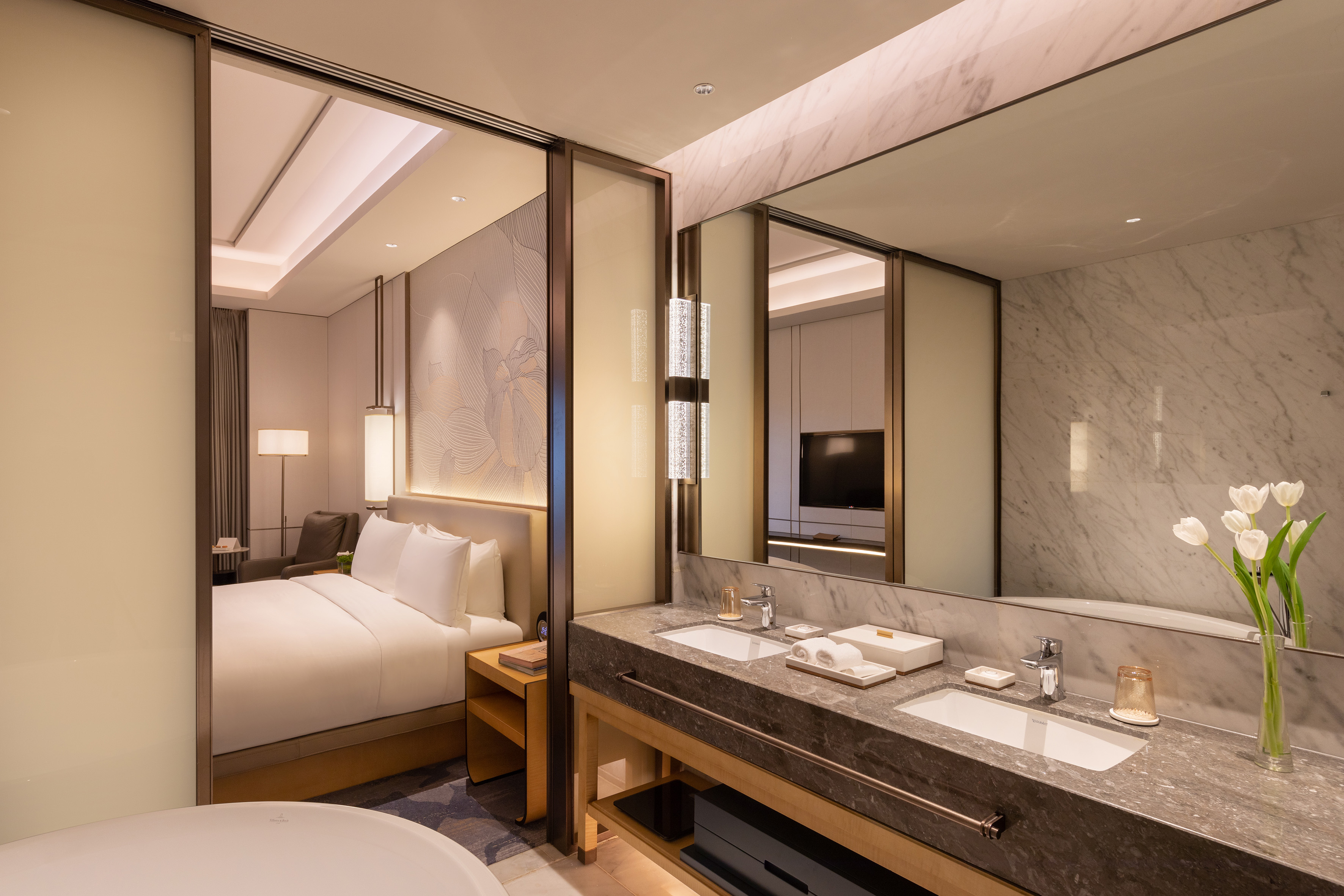 Luxury hotel suite with modern bedroom and double vanity marble bathroom.