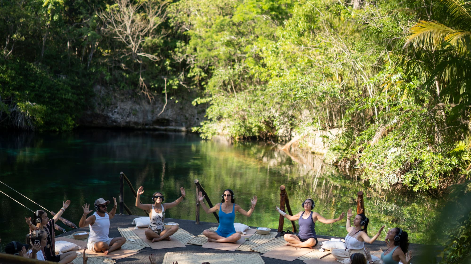 a group of people sitting on mats in front of a body of water