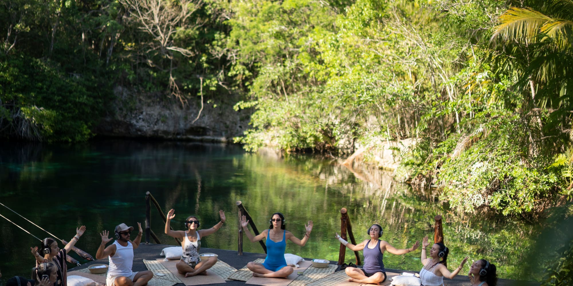 a group of people sitting on mats in front of a body of water