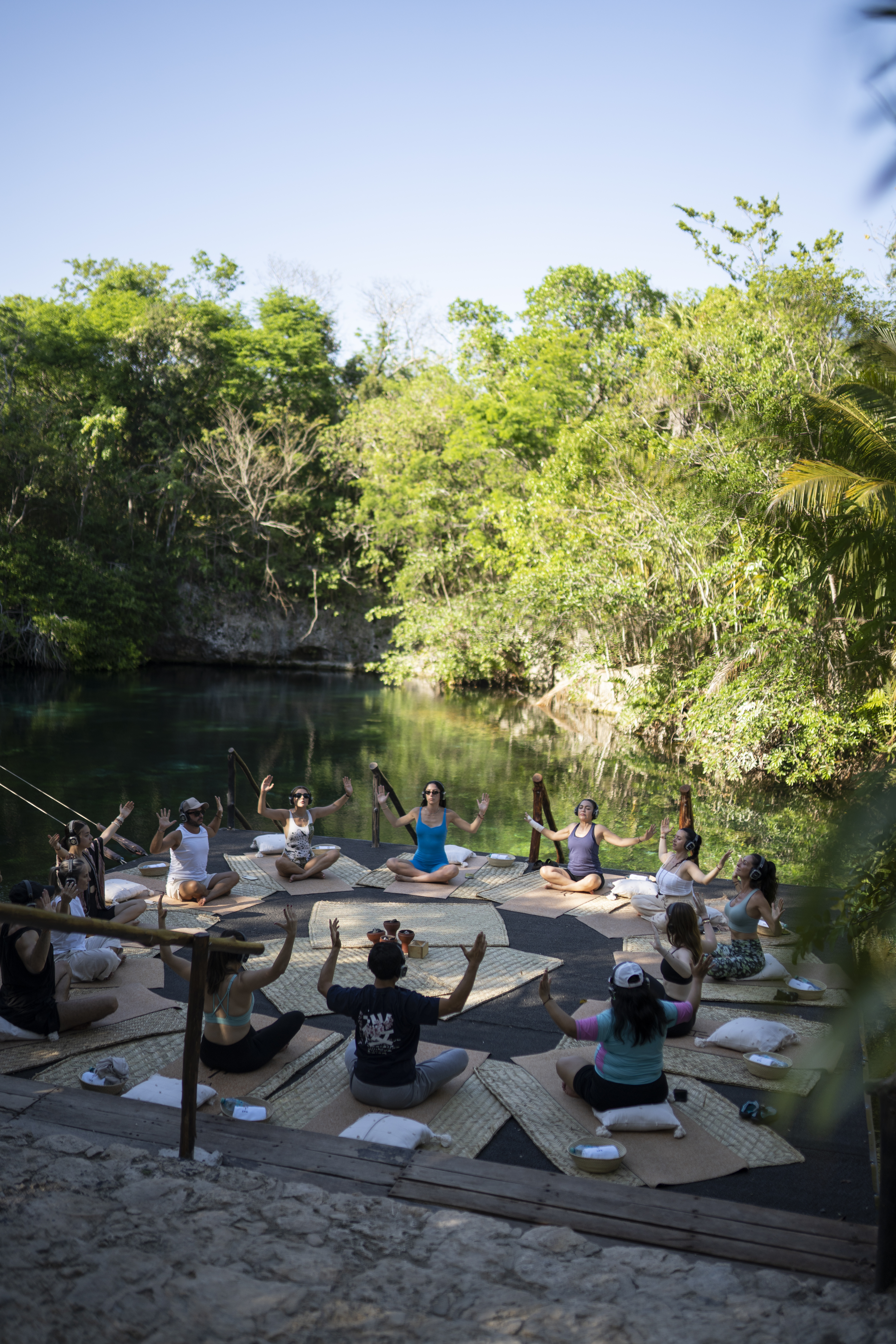 a group of people sitting on mats in front of a body of water.