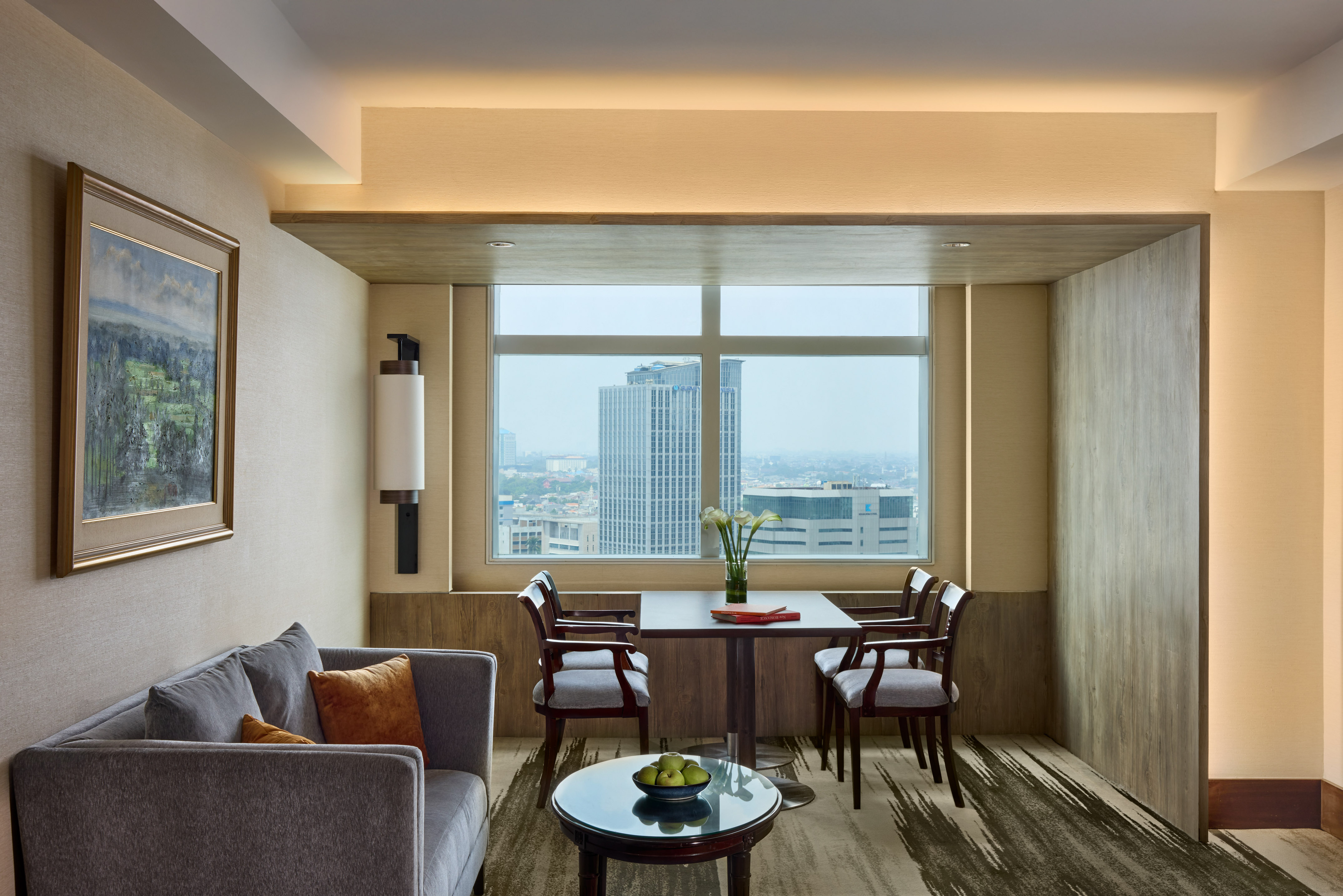 Modern hotel suite living area with city view, sofa, and dining table.