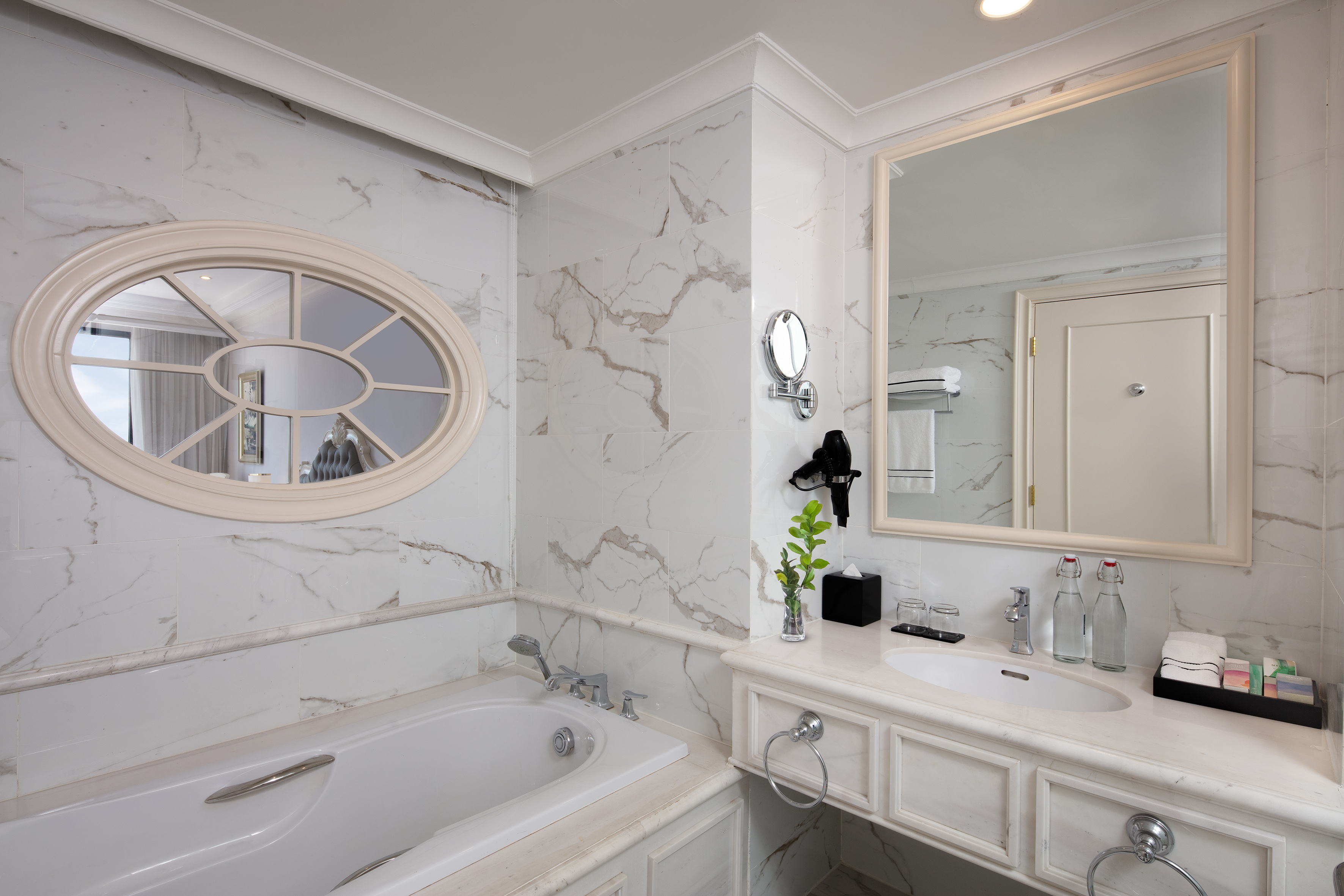 Elegant hotel bathroom with marble walls, bathtub, and vanity.