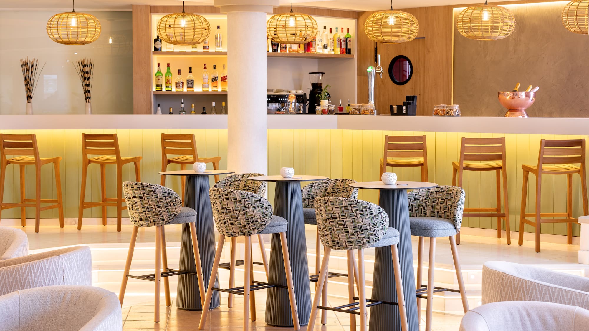 Modern hotel bar lounge, illuminated counter, rattan lights, stylish seating.