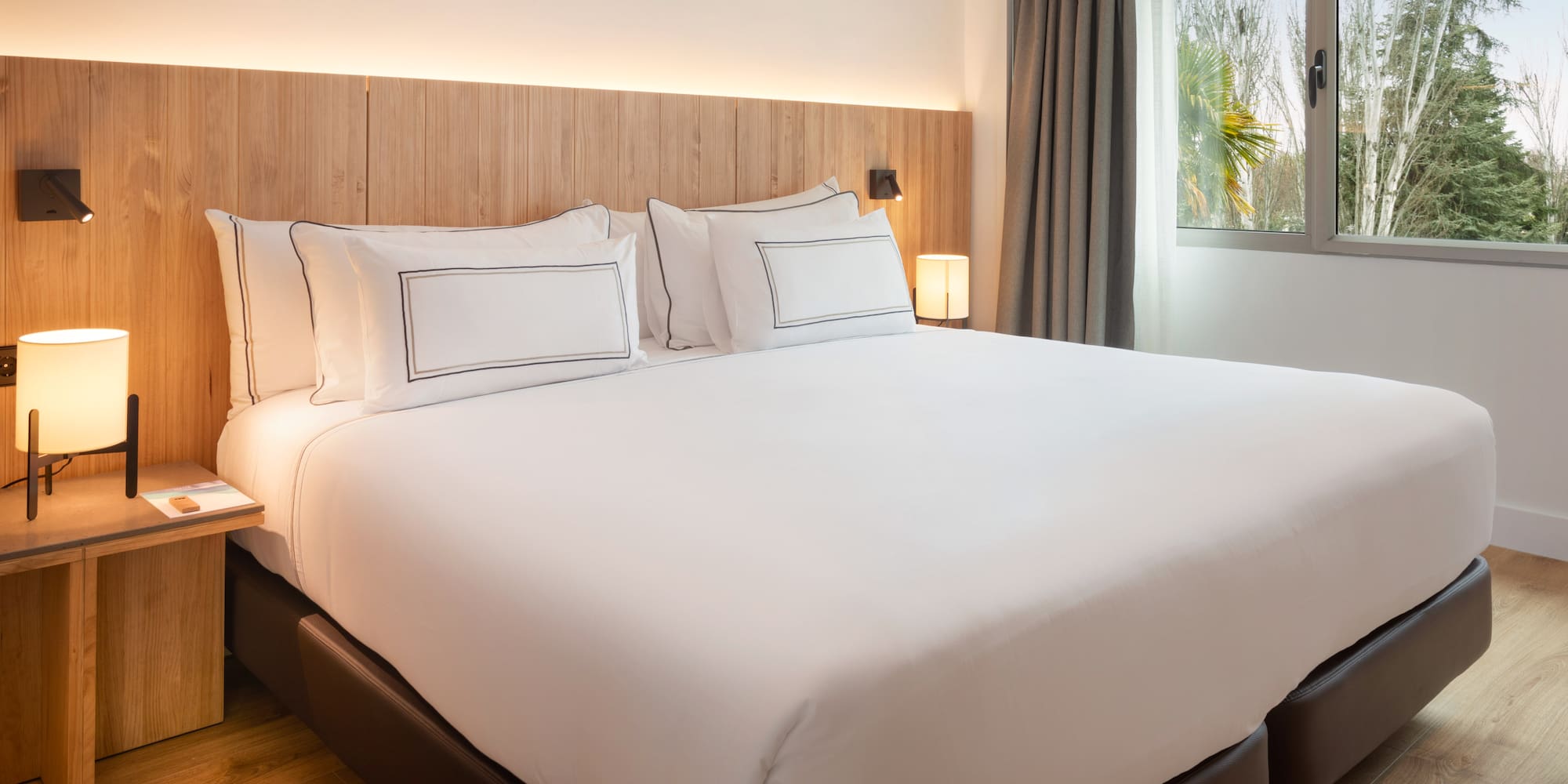 a bed with white sheets and a wood headboard