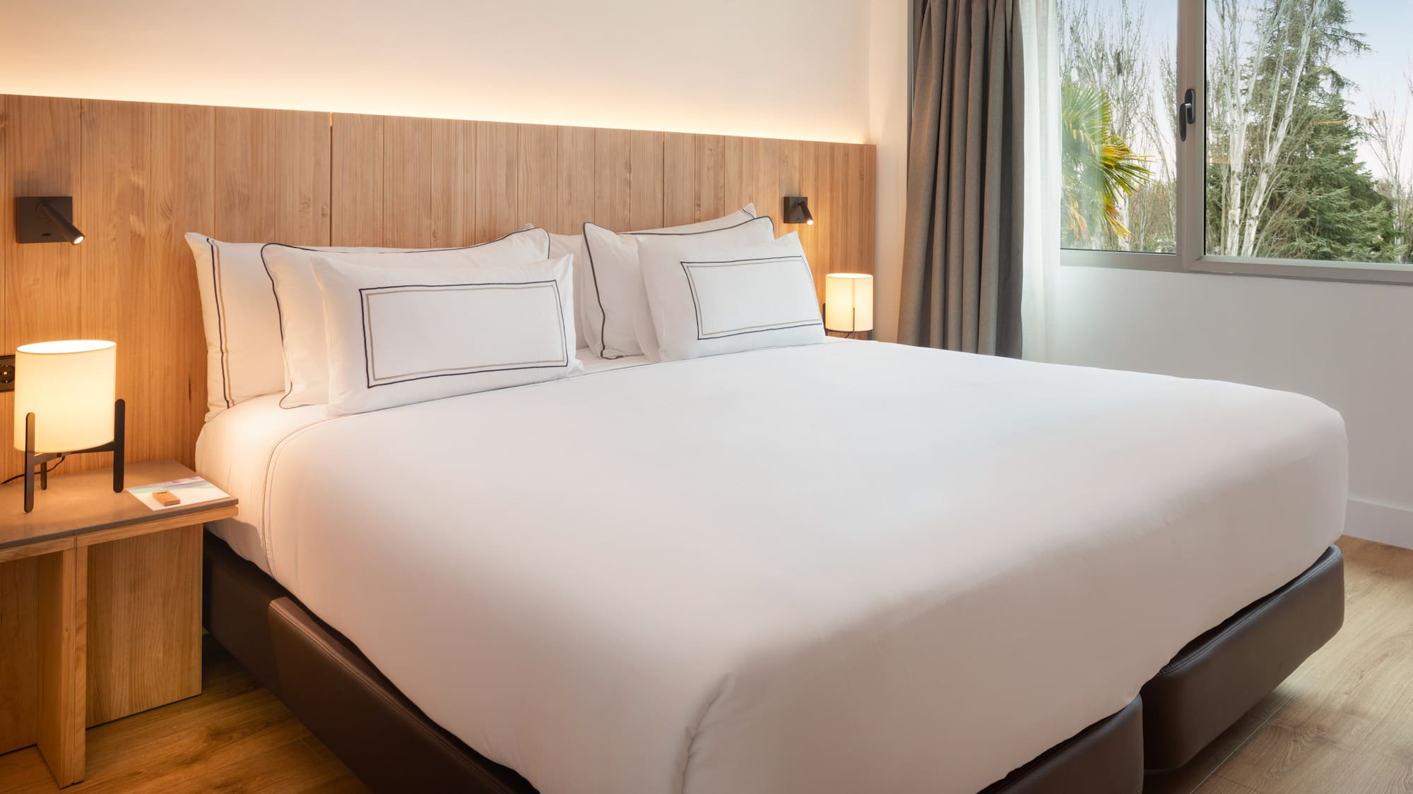 a bed with white sheets and a wood headboard