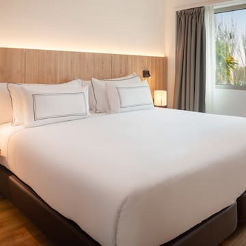 a bed with white sheets and a wood headboard