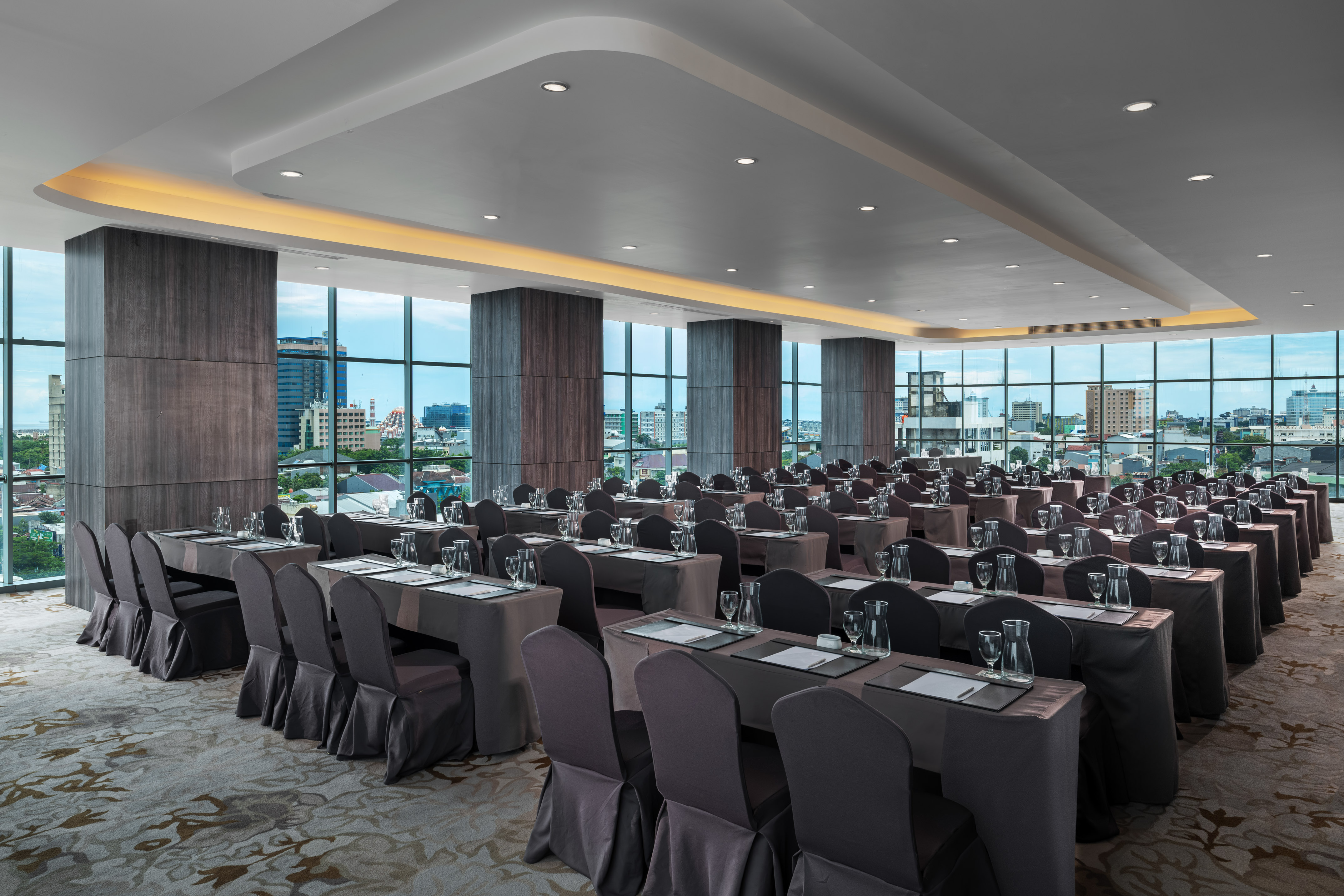 Modern conference room with city view, tables, chairs, and delegate settings.