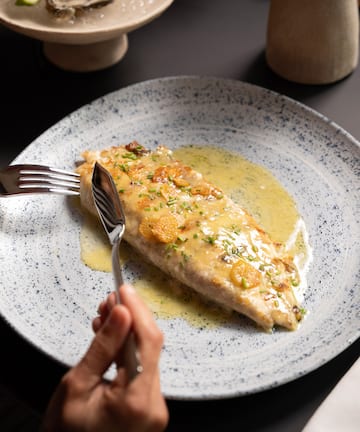 a person eating a fish with a fork and knife