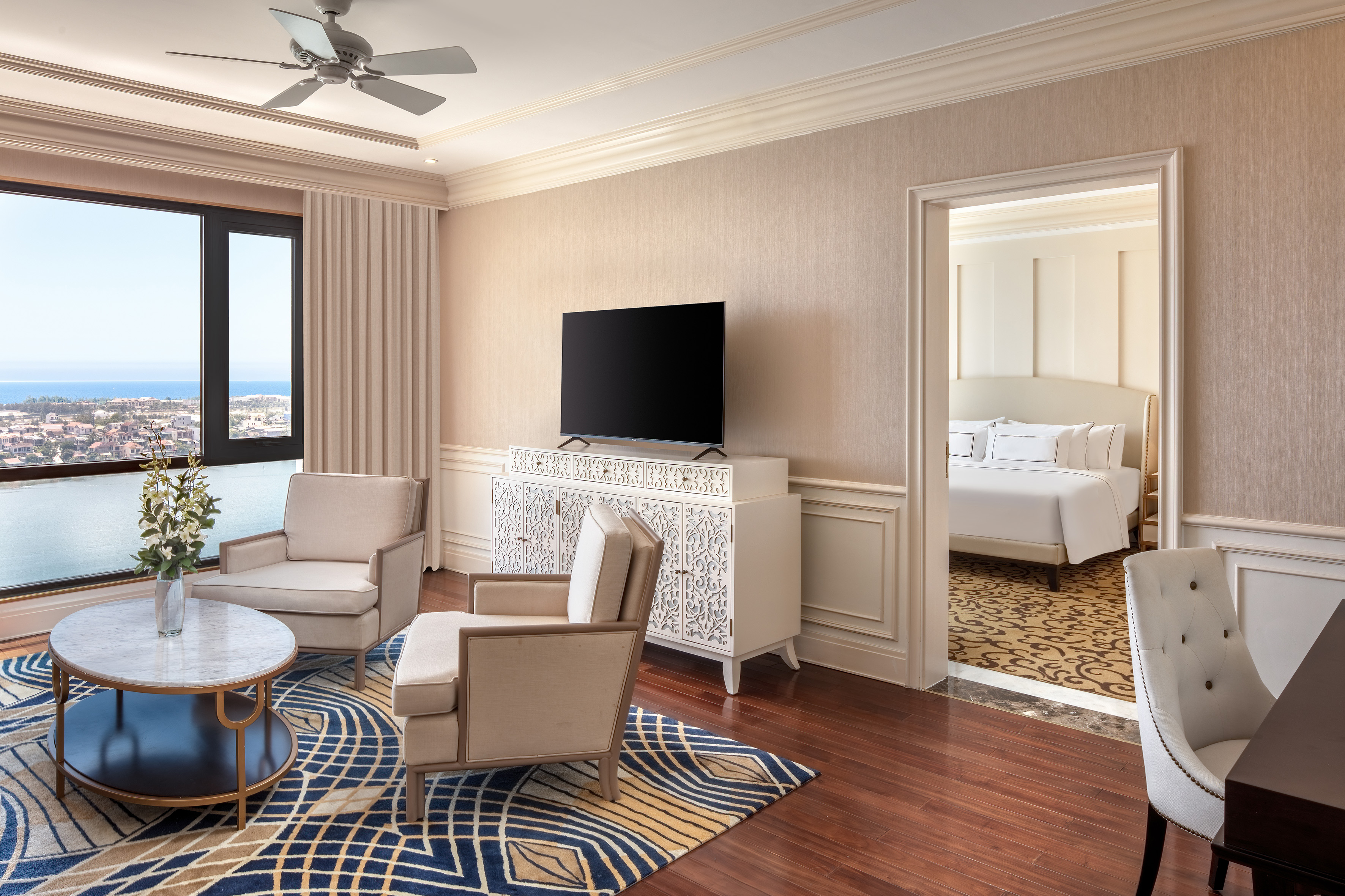 Luxury hotel suite with living room, bedroom, and ocean view.