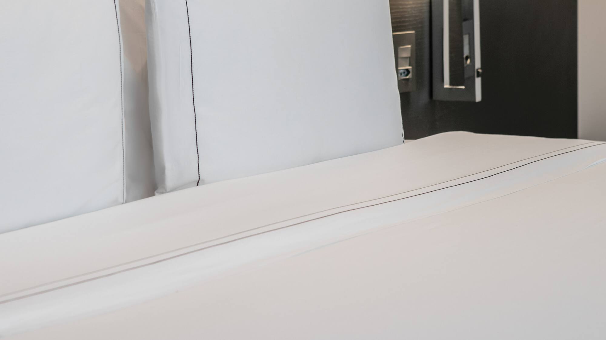 a bed with white sheets and a lamp