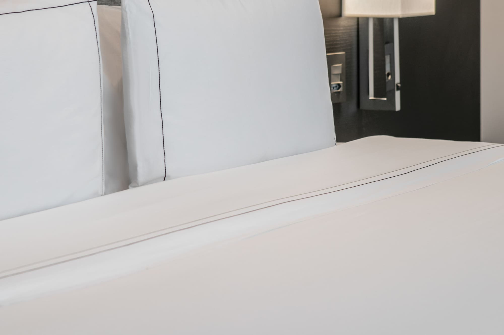 a bed with white sheets and a lamp