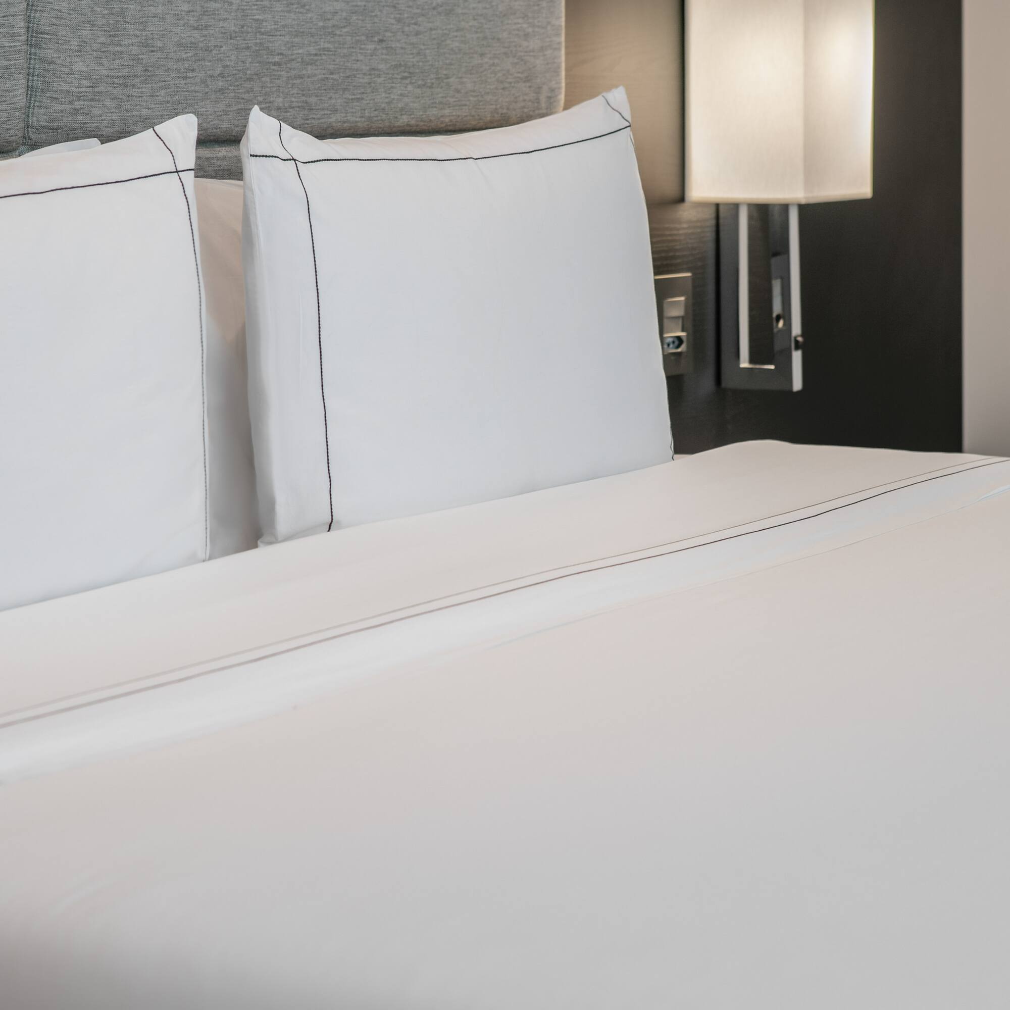 a bed with white sheets and a lamp