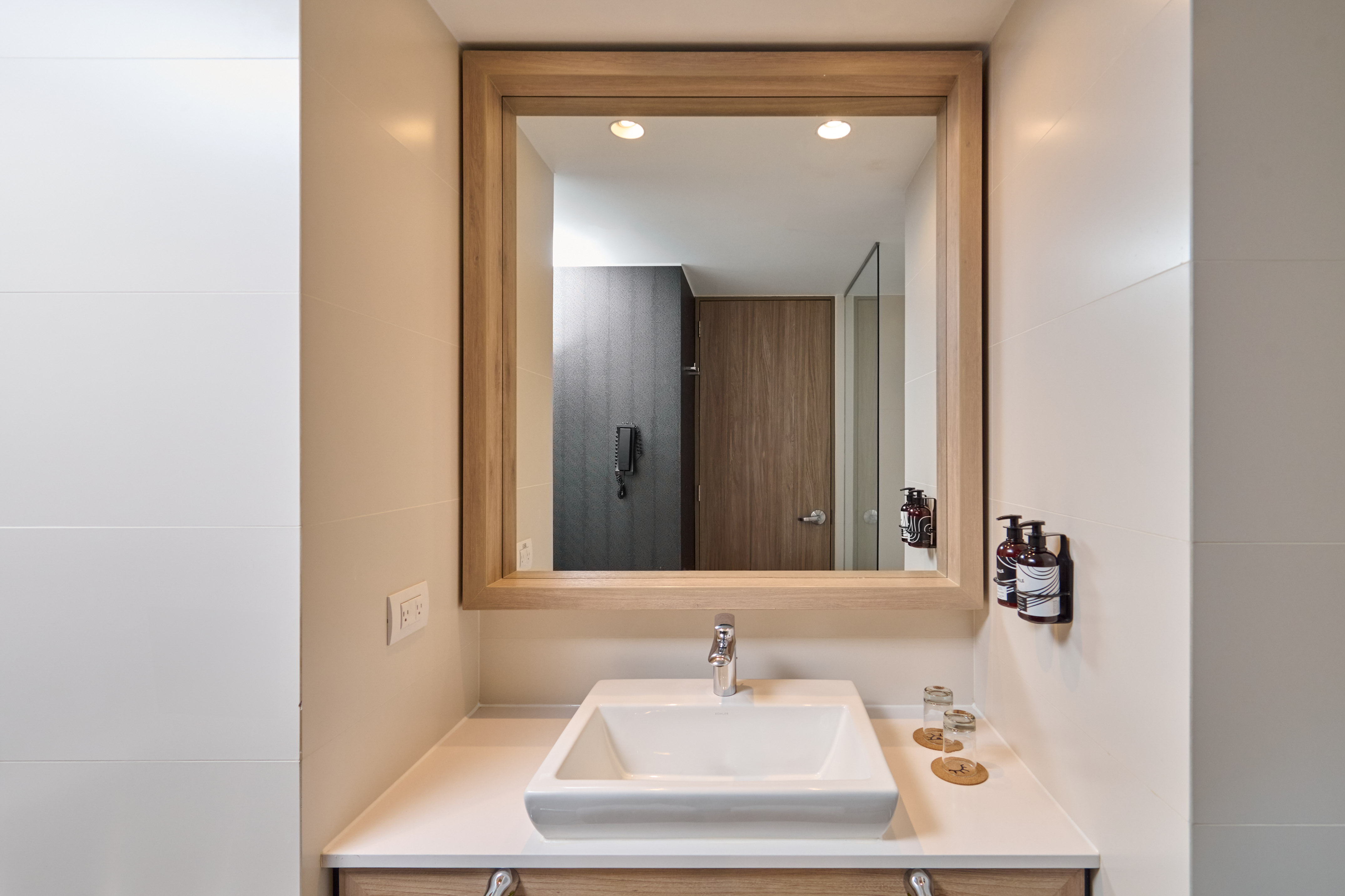 Modern bathroom vanity with white sink, wood mirror, and sleek design.