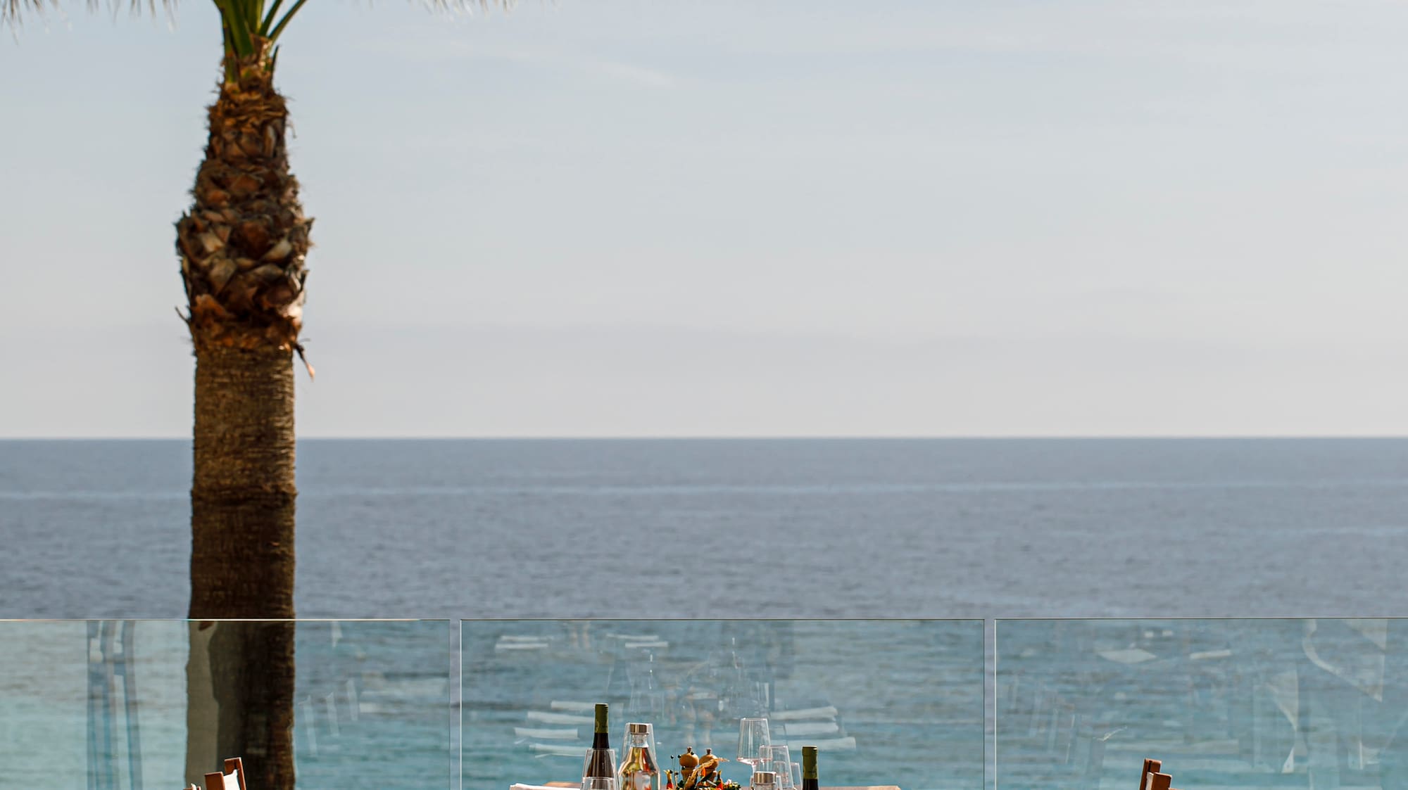 a table set for a dinner with a palm tree and a glass railing