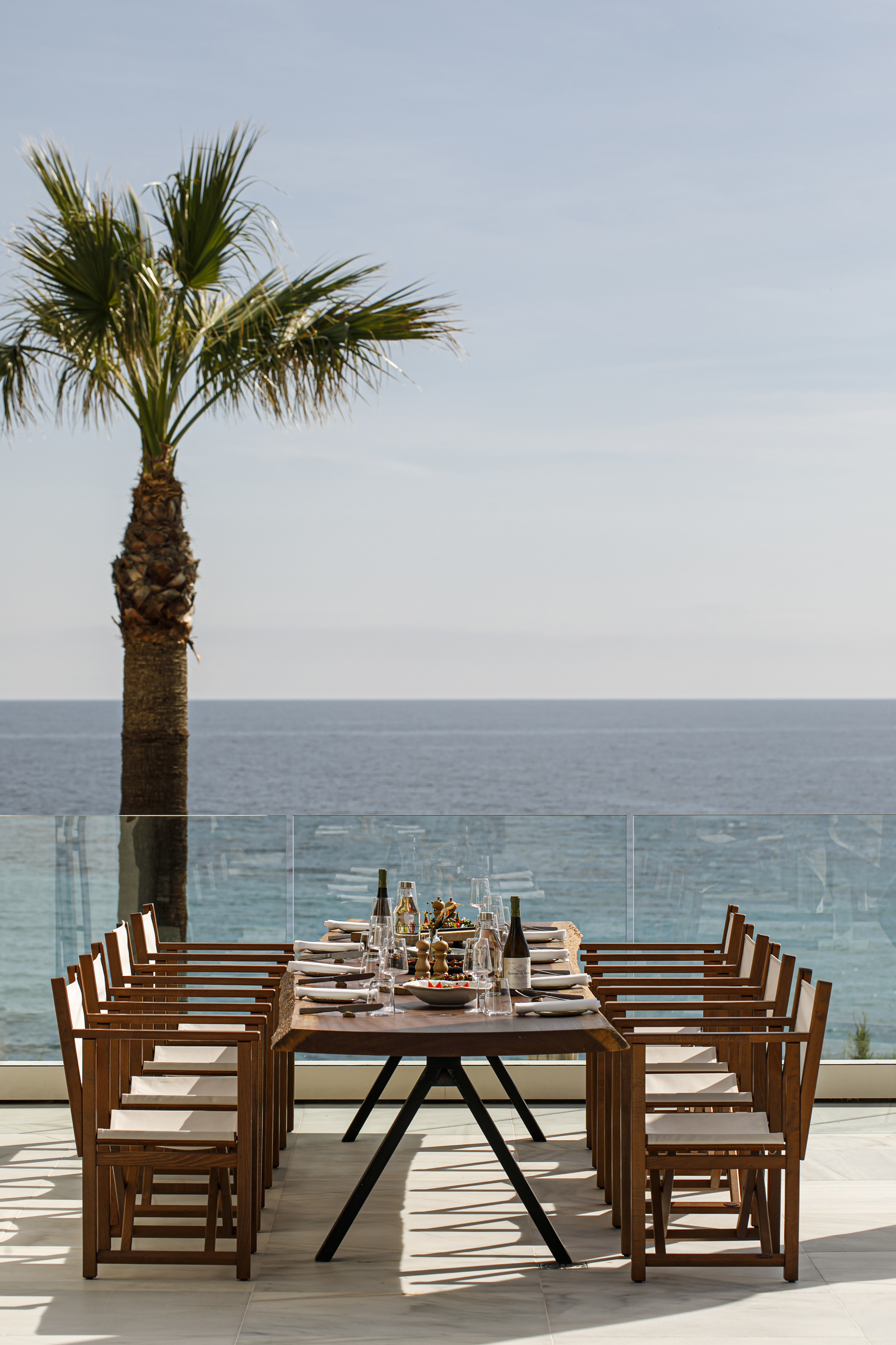 a table set for a dinner with a palm tree and a glass railing
