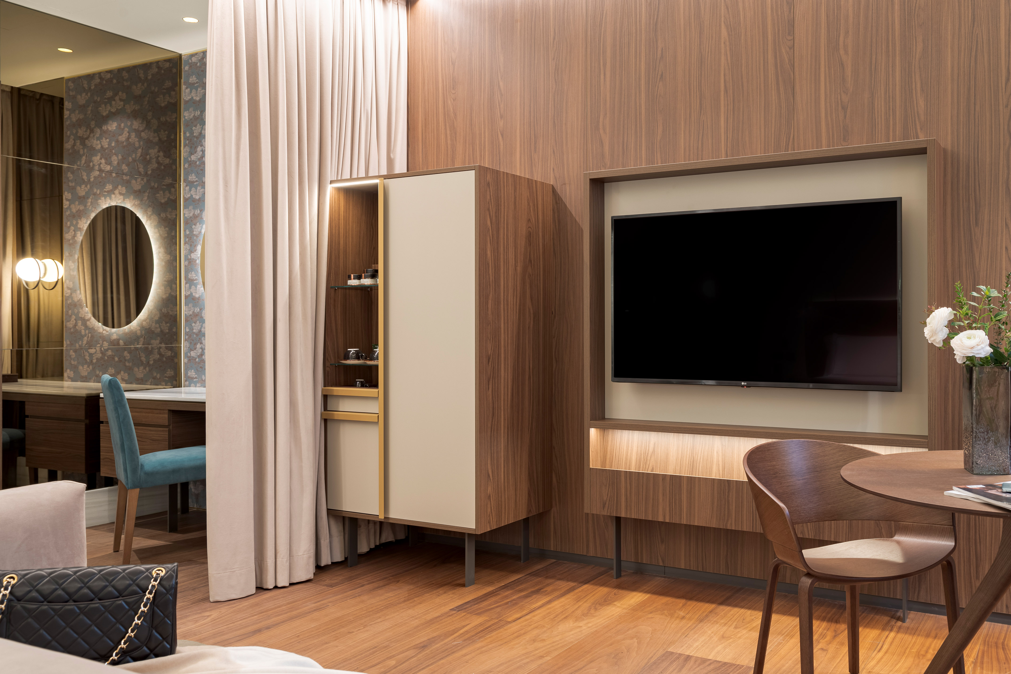 Modern luxury room with wood paneling, built-in TV, vanity, and wardrobe.