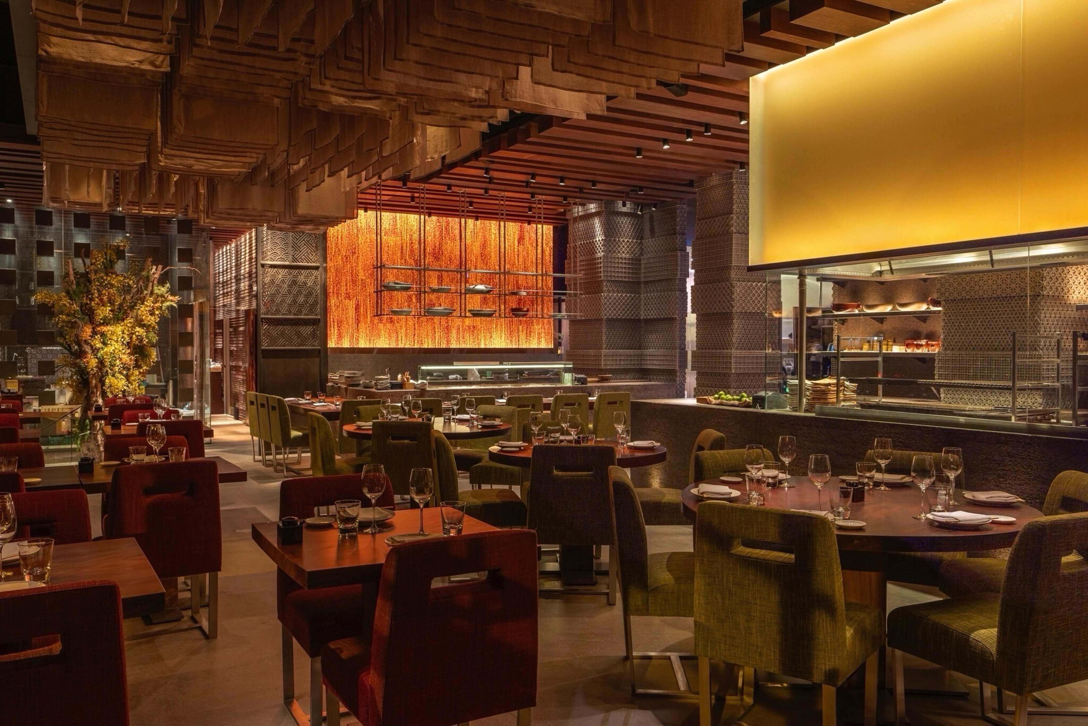 Upscale restaurant dining room with warm lighting, modern design, and open kitchen.