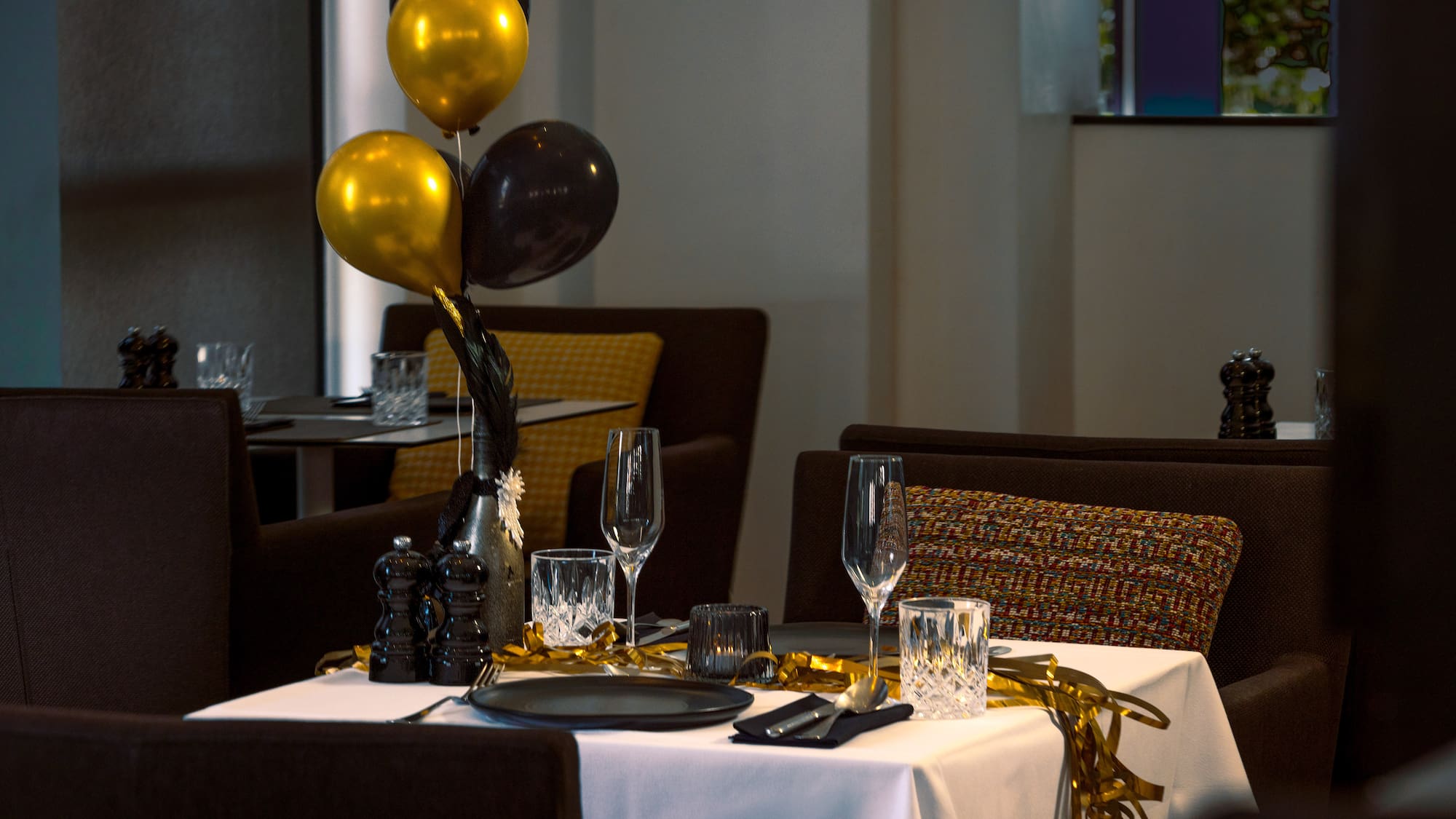 Festive restaurant table with gold and black balloons, elegant place settings.